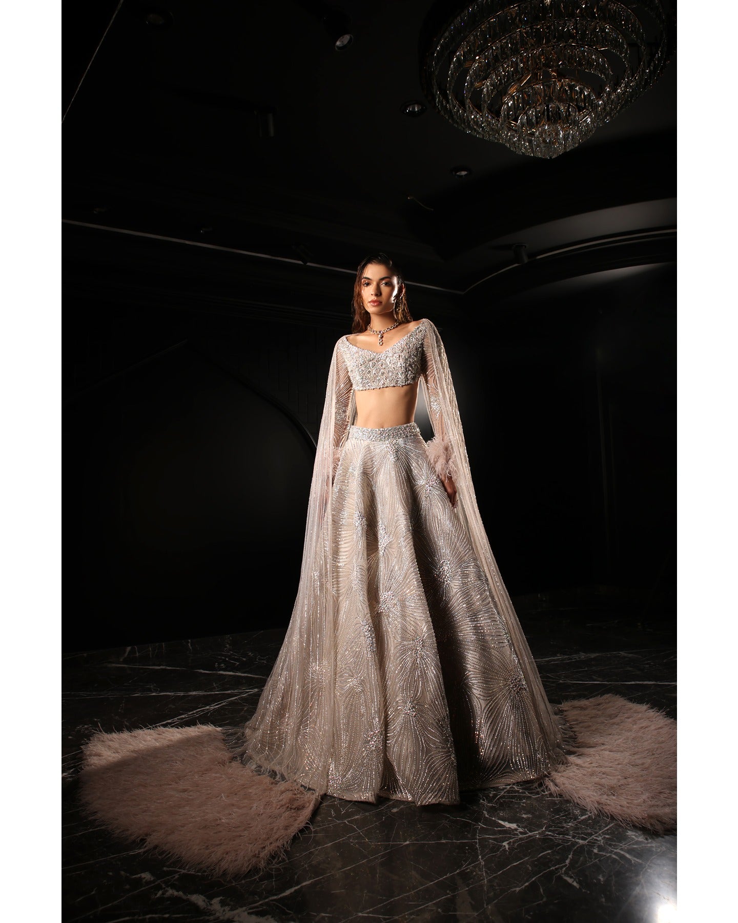 Drenched in lilac sophistication, the Orave lehenga captivates with its V-neck choli blouse and two shoulder trails embellished with Swarovski crystals, feathers, and sequins.