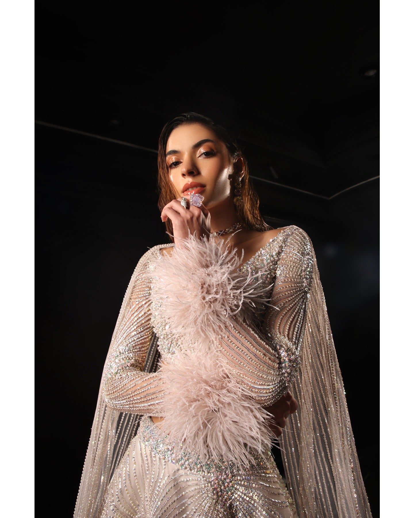 Drenched in lilac sophistication, the Orave lehenga captivates with its V-neck choli blouse and two shoulder trails embellished with Swarovski crystals, feathers, and sequins.