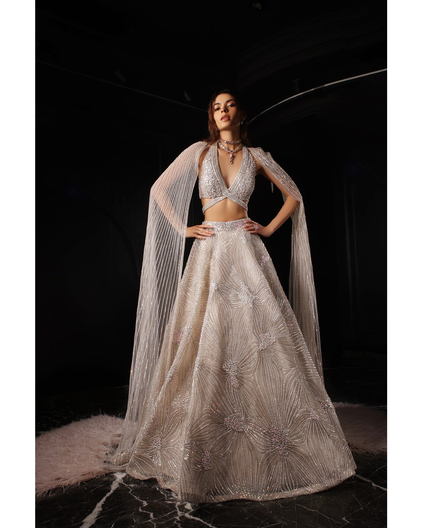 Drenched in lilac sophistication, the Orave lehenga captivates with its V-neck choli blouse and two shoulder trails embellished with Swarovski crystals, feathers, and sequins.