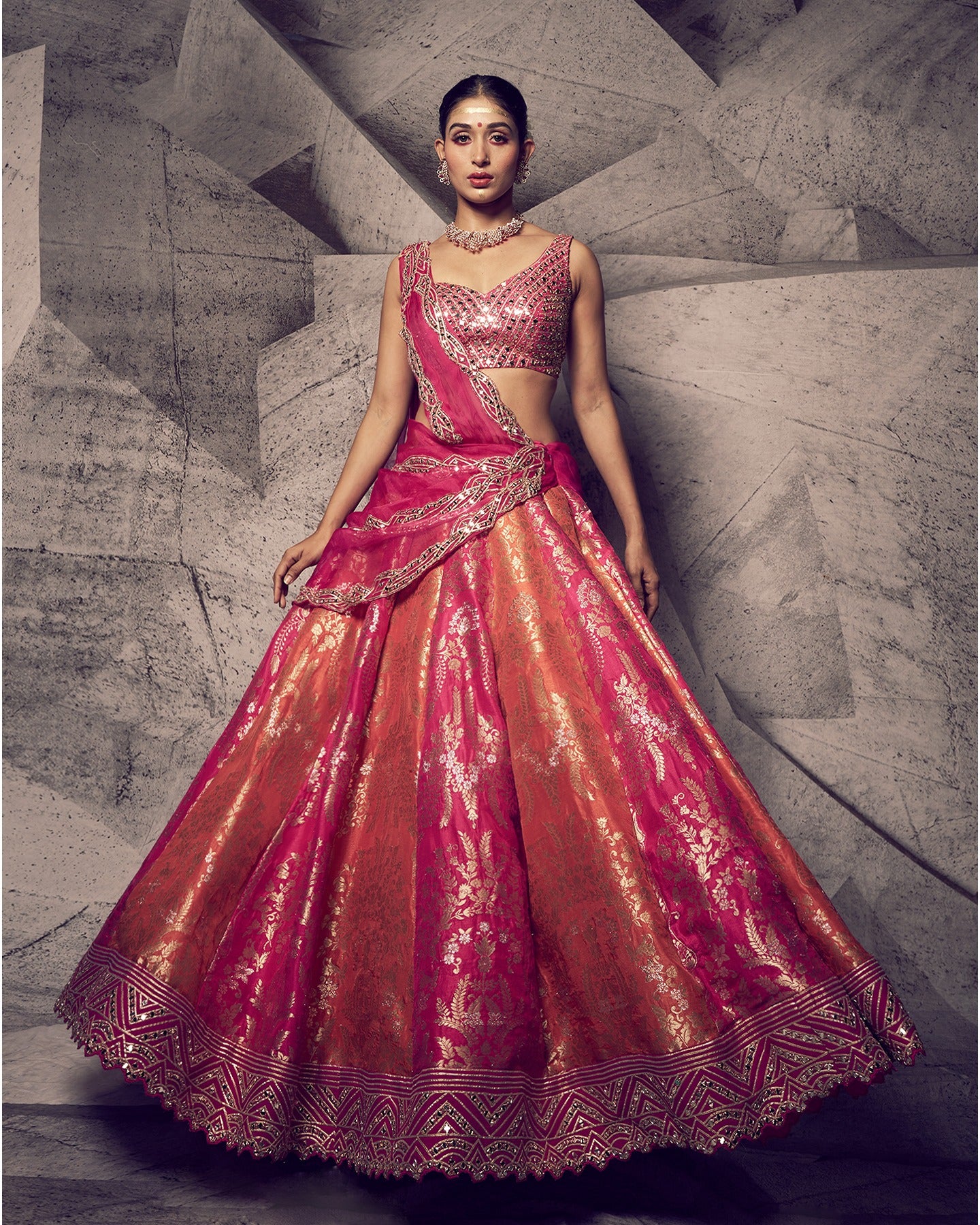 Drenched in the royal hues of rani pink, this lehenga is a symphony of opulent details.