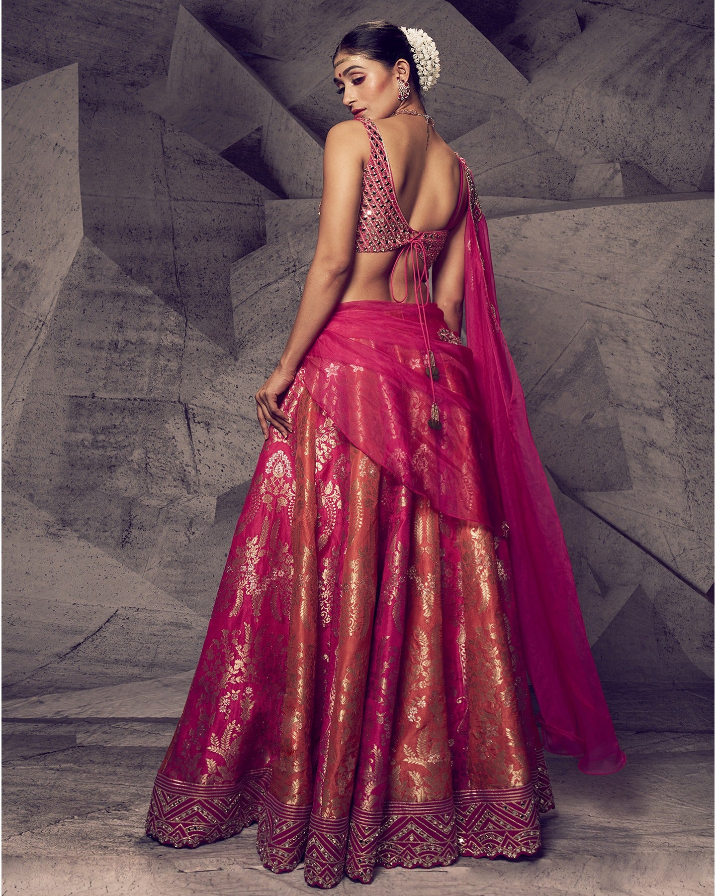 Drenched in the royal hues of rani pink, this lehenga is a symphony of opulent details.