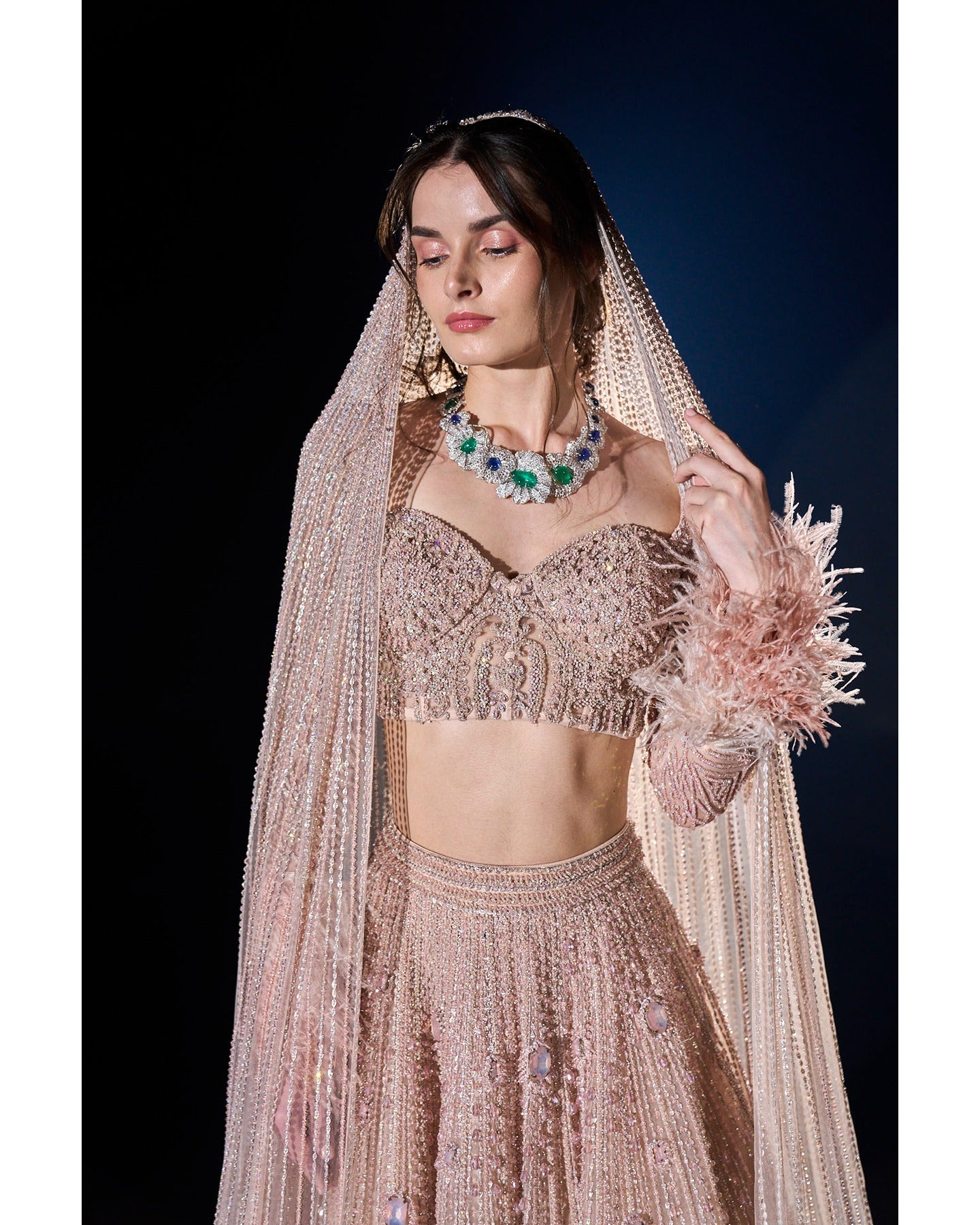 Draped in elegance, our Nude Pink Lehenga intricately embellished with stones, crystals, sequins, and Japanese cut-dana, unveils a timeless symphony of grace and sophistication.