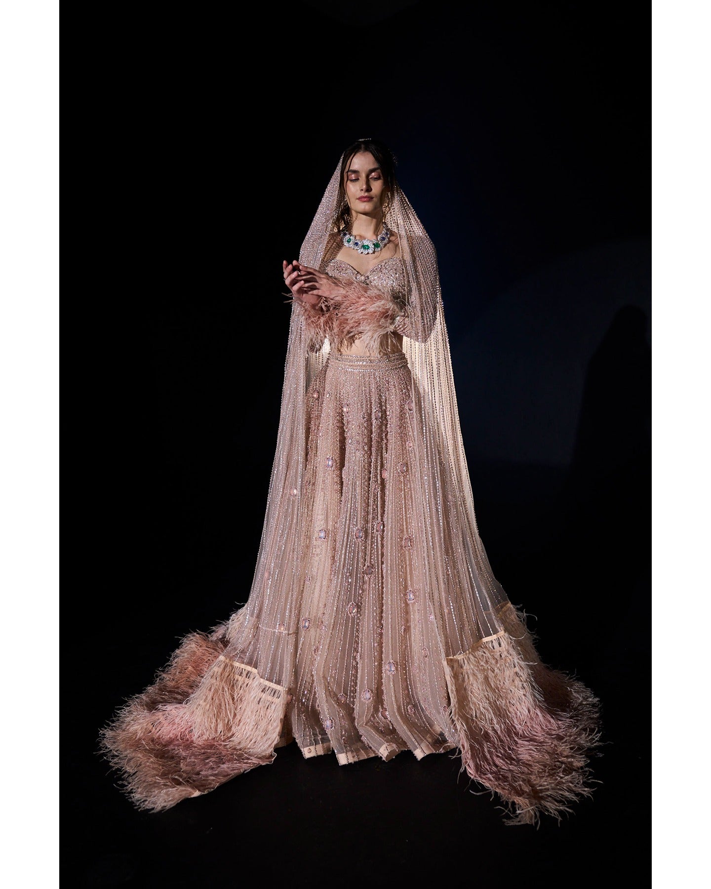 Draped in elegance, our Nude Pink Lehenga intricately embellished with stones, crystals, sequins, and Japanese cut-dana, unveils a timeless symphony of grace and sophistication.