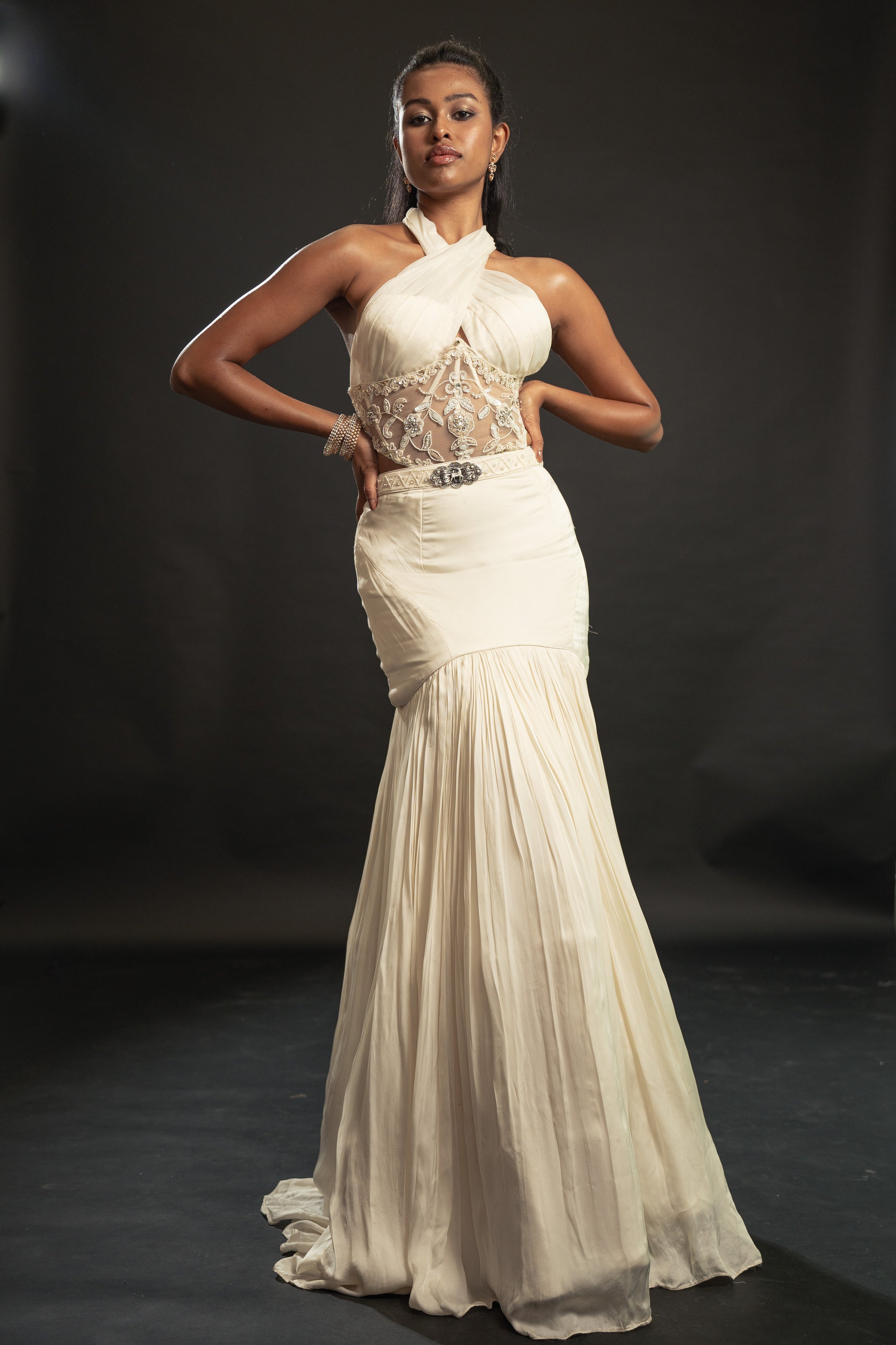 Unleash your inner goddess in this Ivory Fishcut Skirt Lehenga Set, adorned with a satin silk skirt, shimmering Organza blouse, and a mesmerizing Organza cape