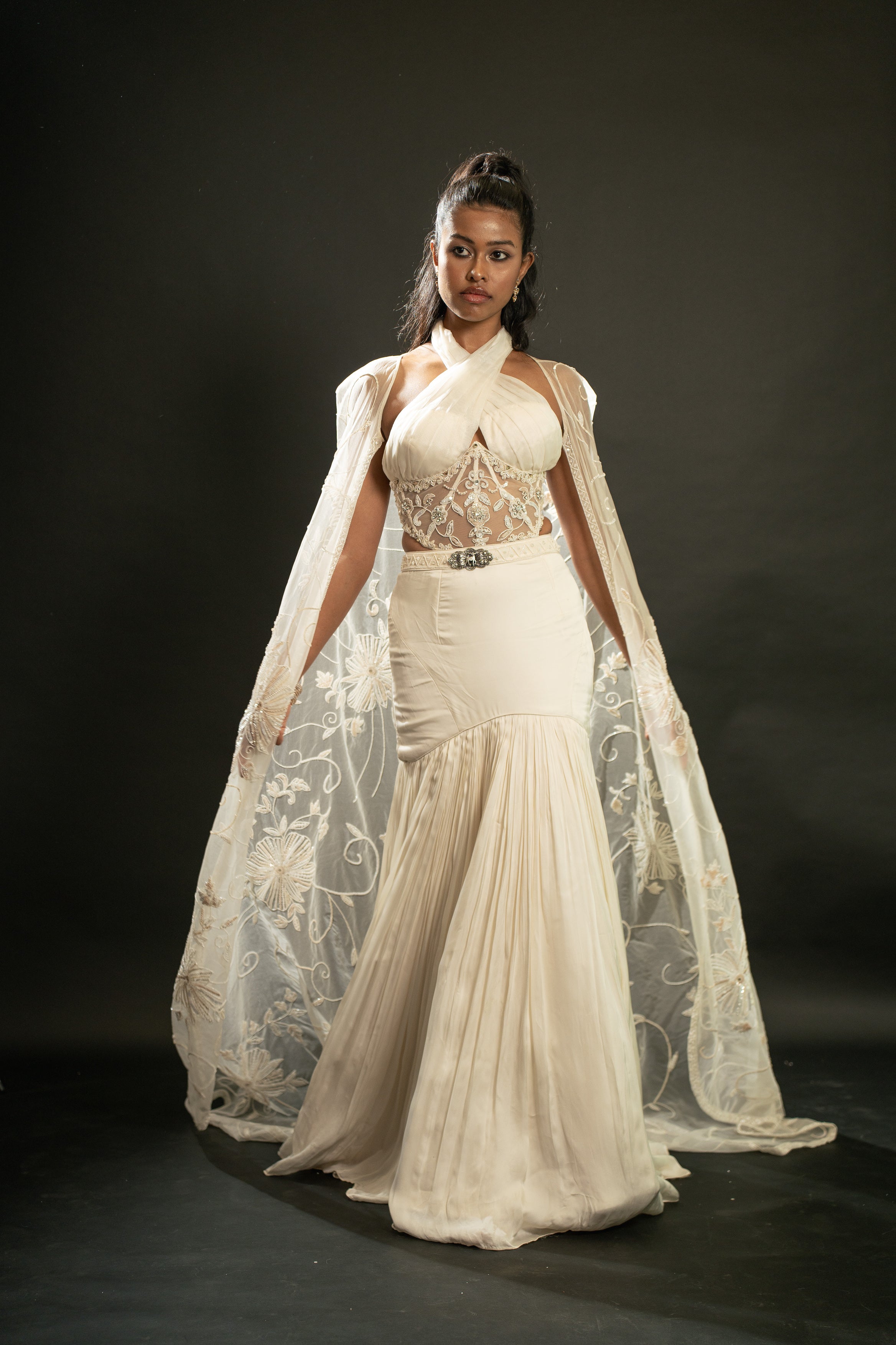 Elegance redefined: Dive into luxury with this Ivory Fishcut Skirt Lehenga Set, featuring a lustrous Satin Silk skirt, shimmering Organza blouse, and delicate Organza cape.