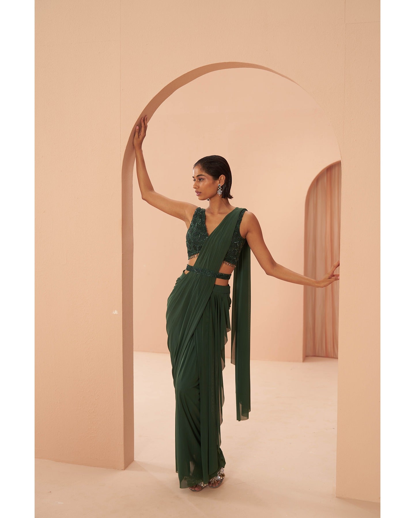 Bottled Beauty: Hand-embroidered elegance adorns this bottle green drape saree, a captivating symphony of sophistication.