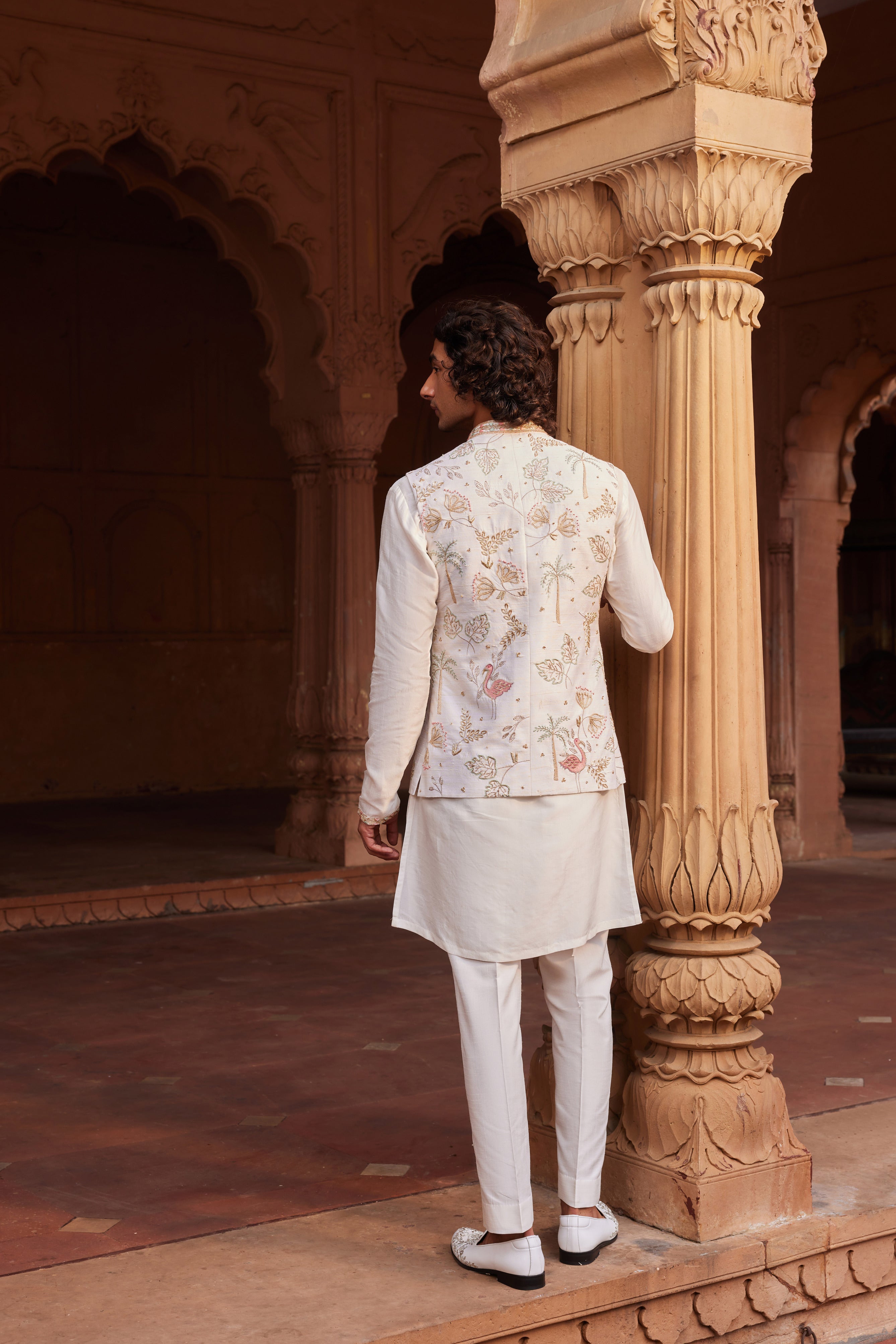 A stunning Flamingo Nehru Jacket embellished with rich, multi-colored resham threads, gleaming zari, ornate zardozi, and delicate dabka work, highlighted by a series of unique, eye-catching motifs. Paired perfectly with an elegant, well-detailed kurta and sleek pants, this set is a statement in craftsmanship and style.