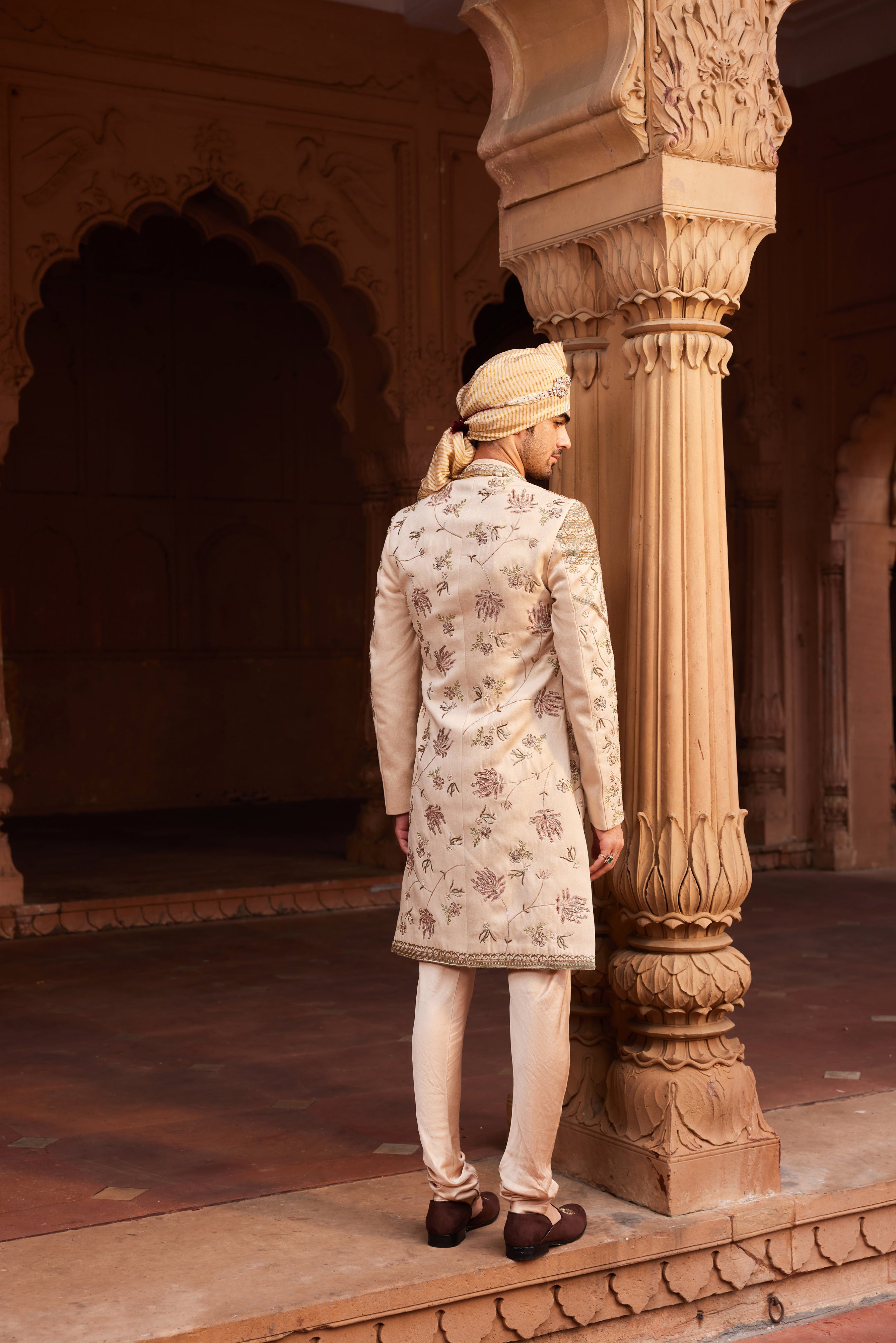 Full view of an intricately embellished sherwani with geometric and floral motifs, paired with coordinating kurta, pants, and a richly embroidered stole.