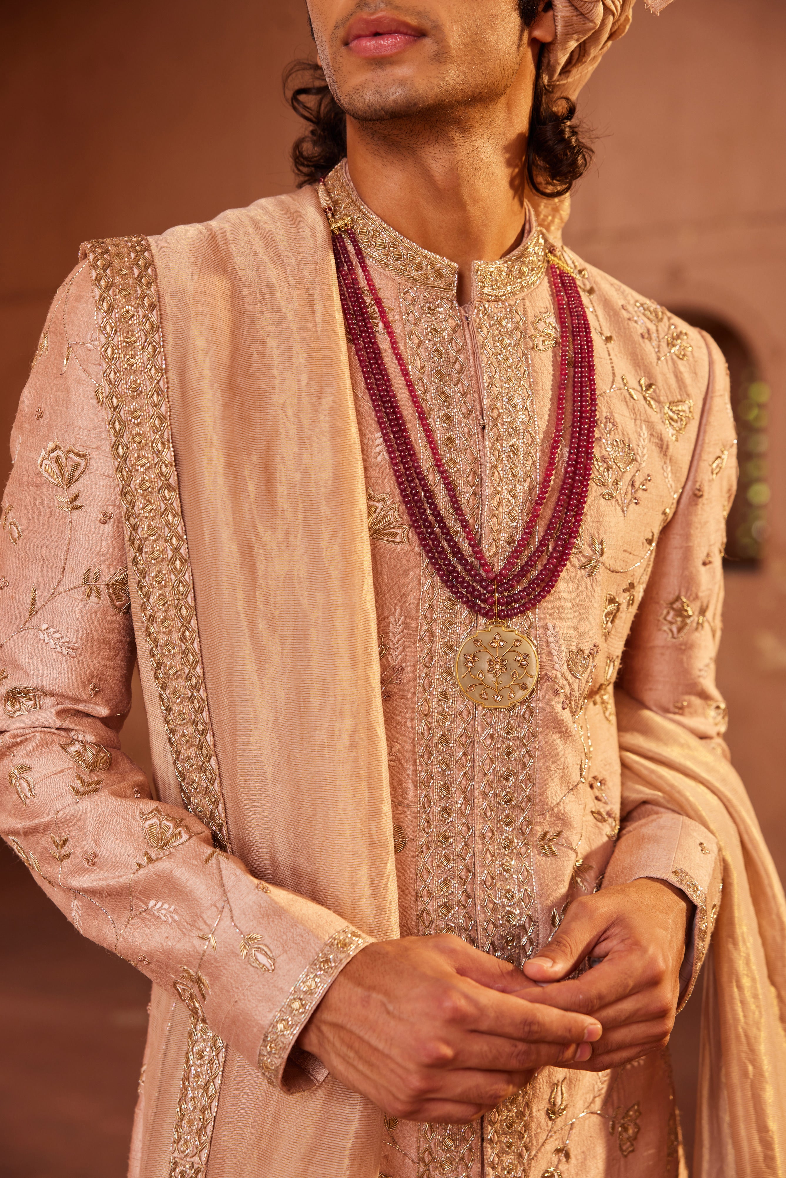 Full view of a sherwani with exquisite floral and center border detailing, enhanced by intricate embroidery, paired with a kurta, pants, and an elegant embroidered stole.