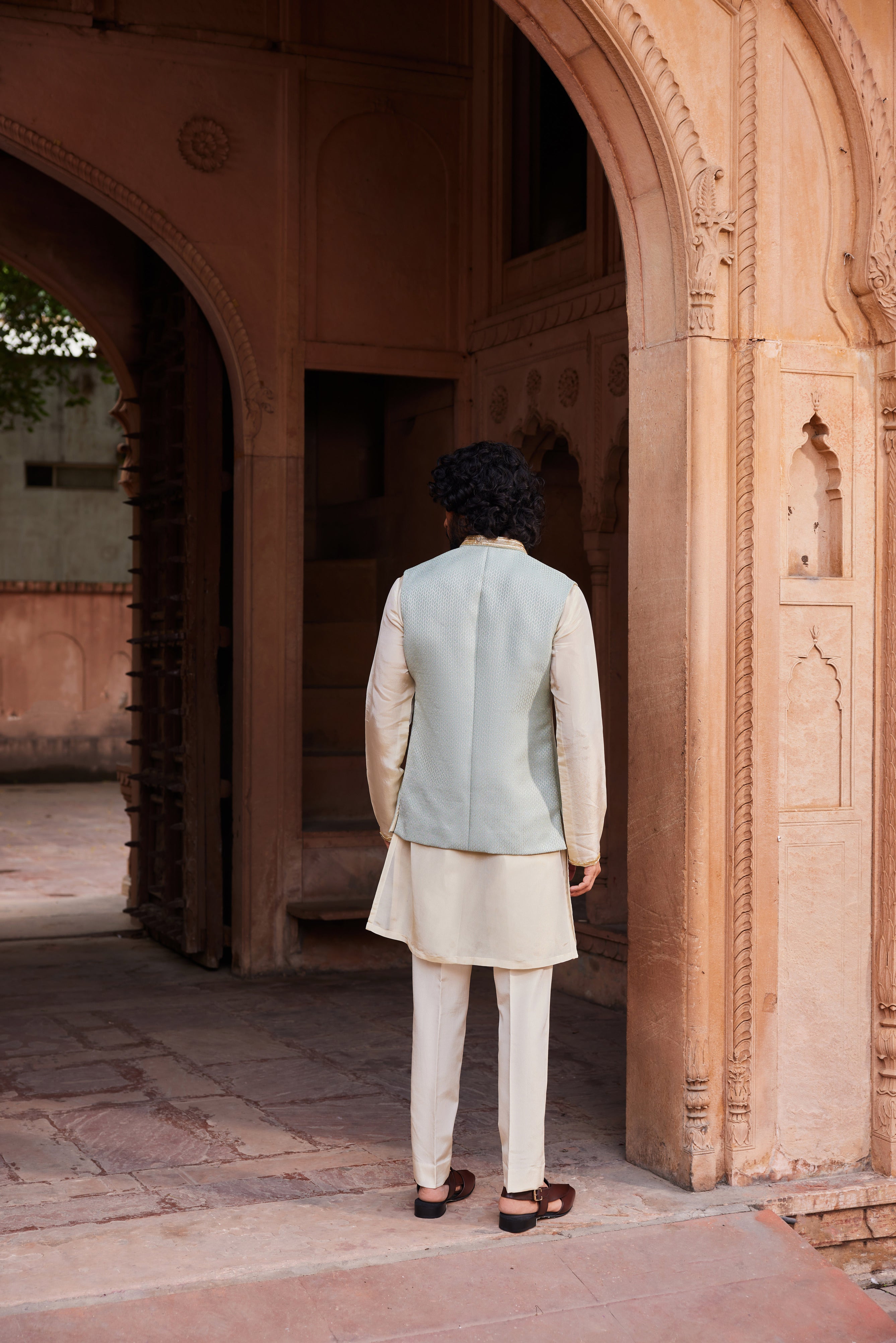 A sophisticated Nehru jacket with intricate embroidery on the collar, creating a striking contrast against the soft beige kurta and matching pants. This ensemble exudes a subtle yet elegant charm, perfect for formal or traditional occasions.