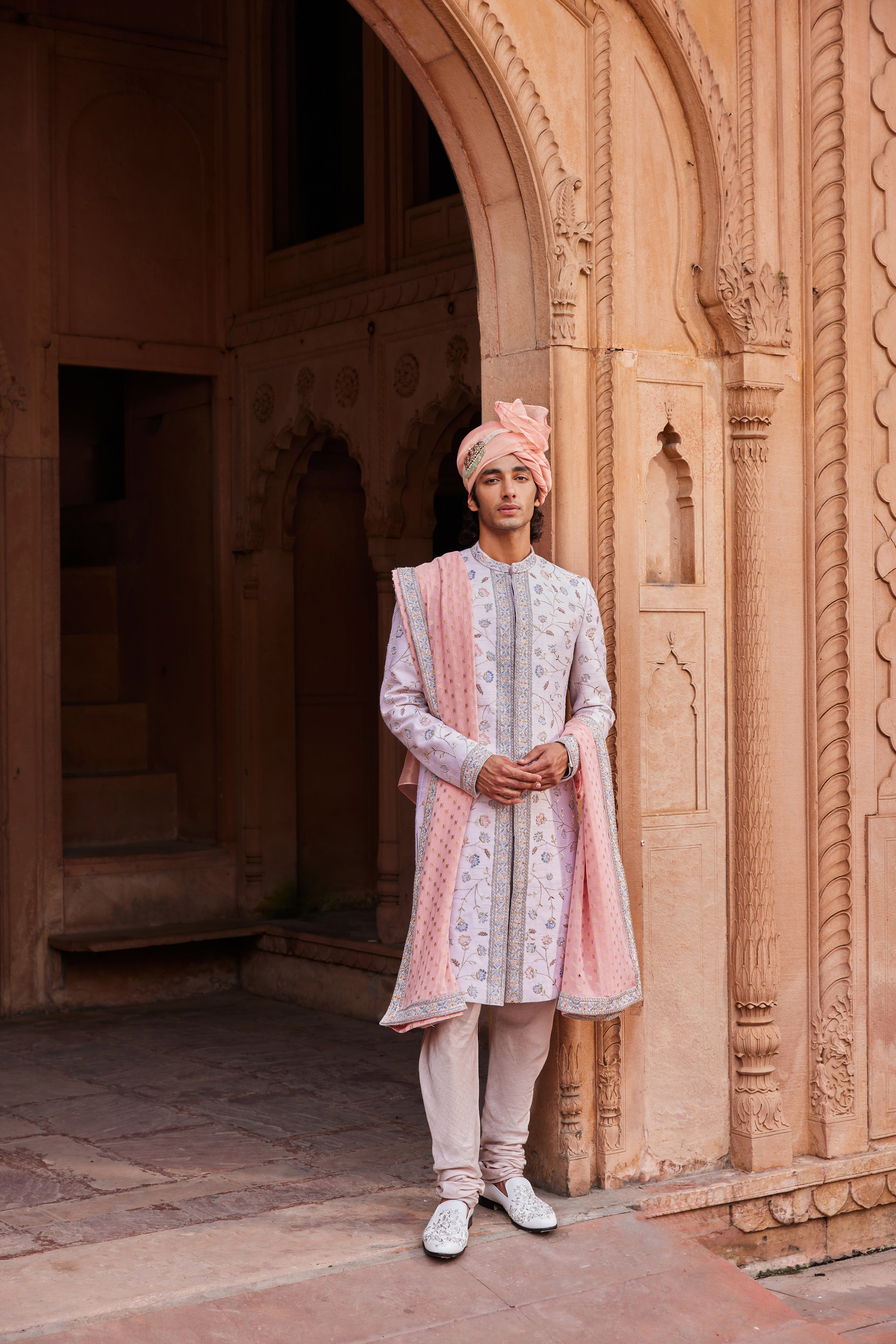 Close-up of a sherwani showcasing intricate resham, zari, zardozi, and dabka embroidery with floral and symmetrical designs, paired with a matching kurta, pants, and an embroidered stole