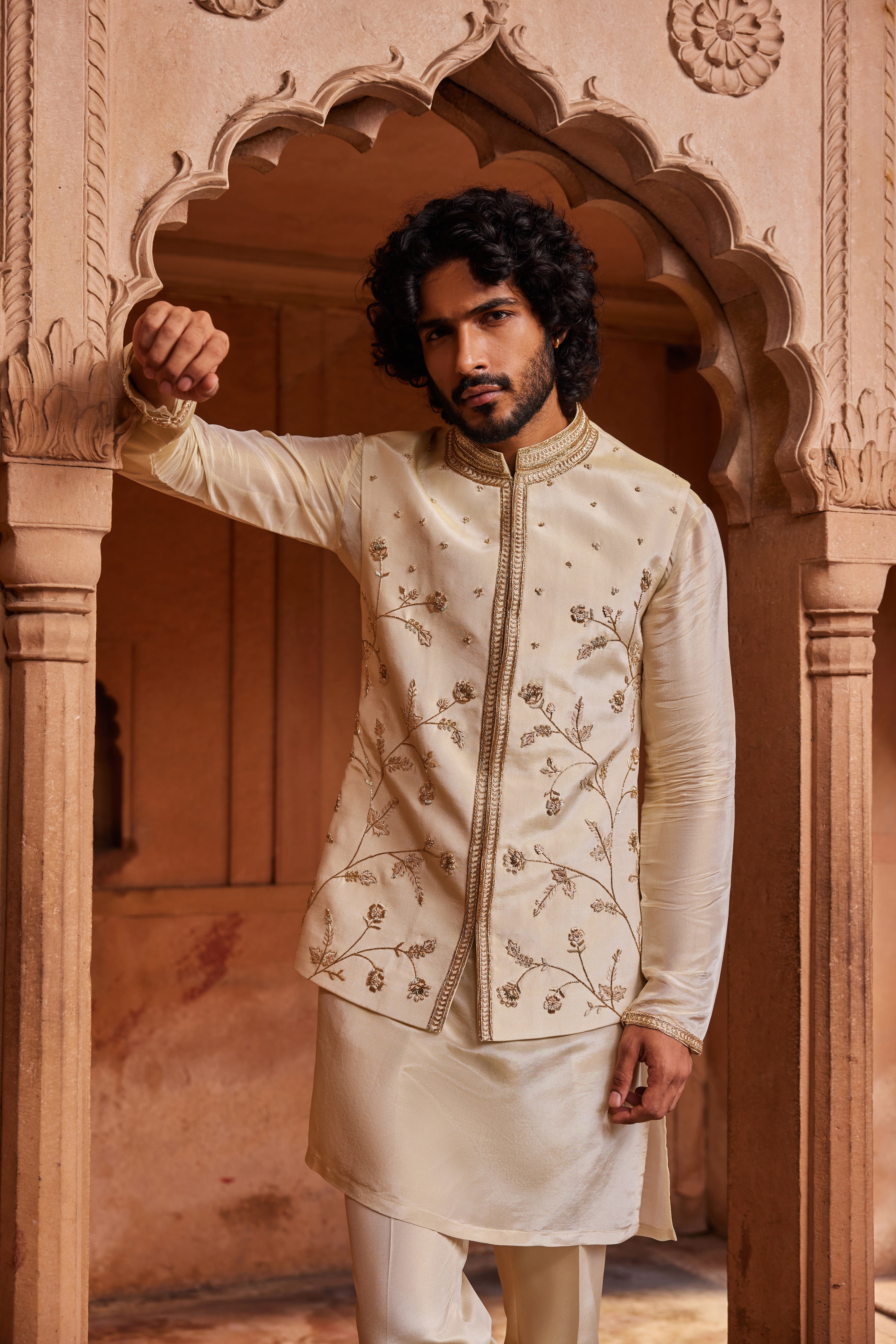 A Nehru jacket featuring delicate floral designs with intricate zardozi, dabka, and zari handwork, paired with a monotone kurta and pants for a refined, cohesive look.