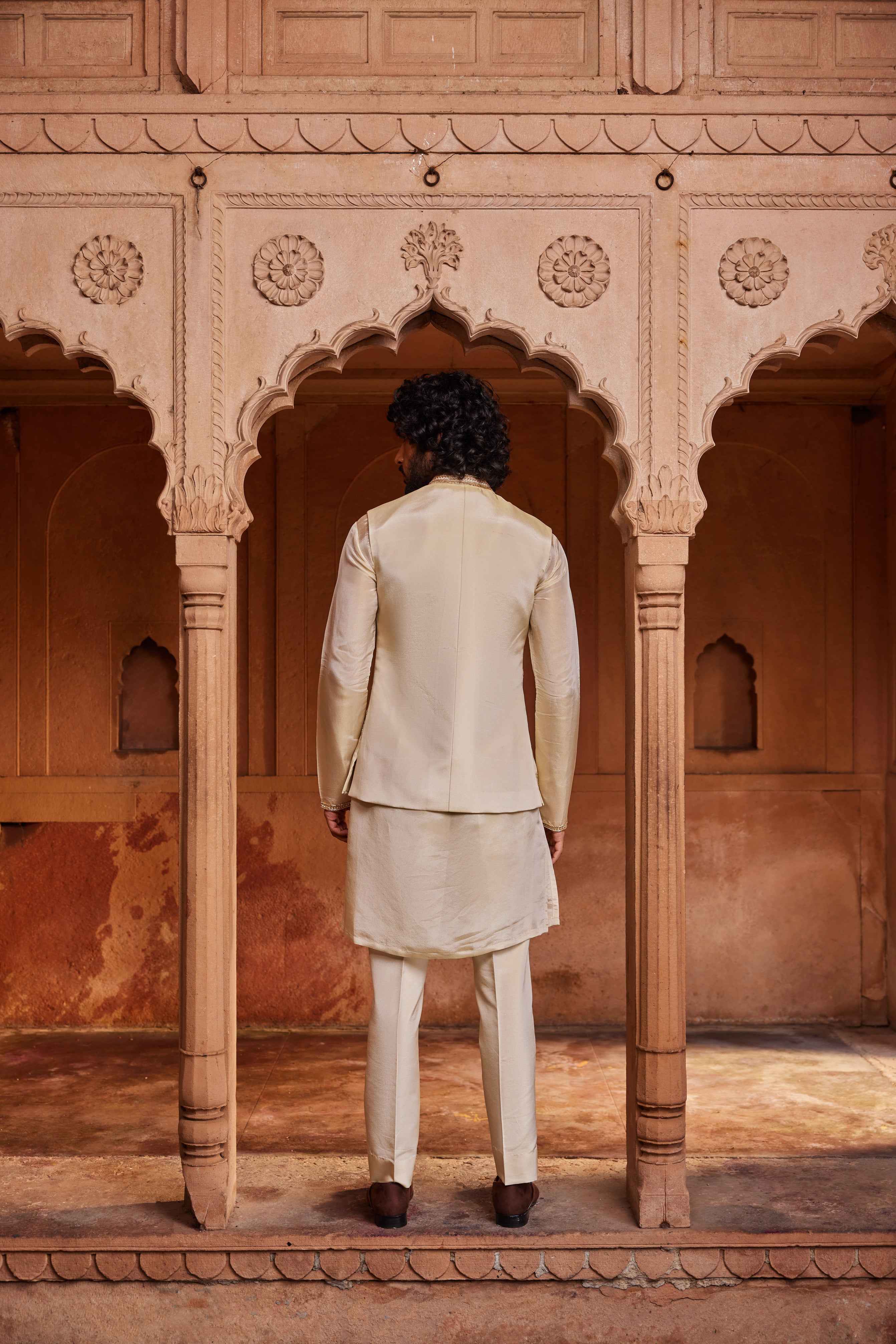 A luxurious Nehru jacket embellished with intricate floral zardozi, dabka, and shimmering zari handwork, paired with a detailed monotone kurta and matching pants. The ensemble exudes elegance, blending rich craftsmanship with understated sophistication.
