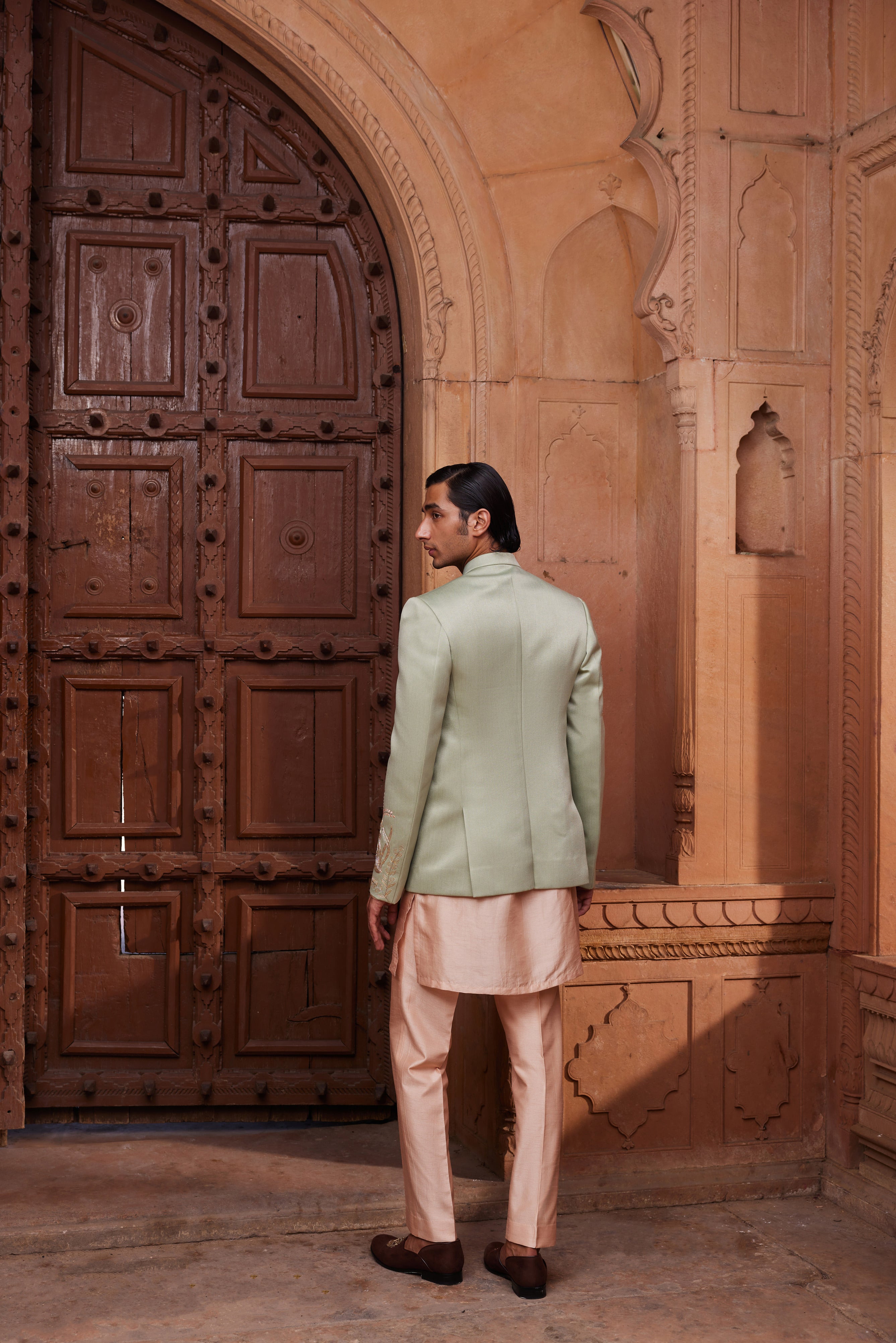 The Ruhaab Jacket Set includes a jacket embellished with floral motifs in dori, zari, and zardozi embroidery, paired with a contrasting kurta and pants for a refined look