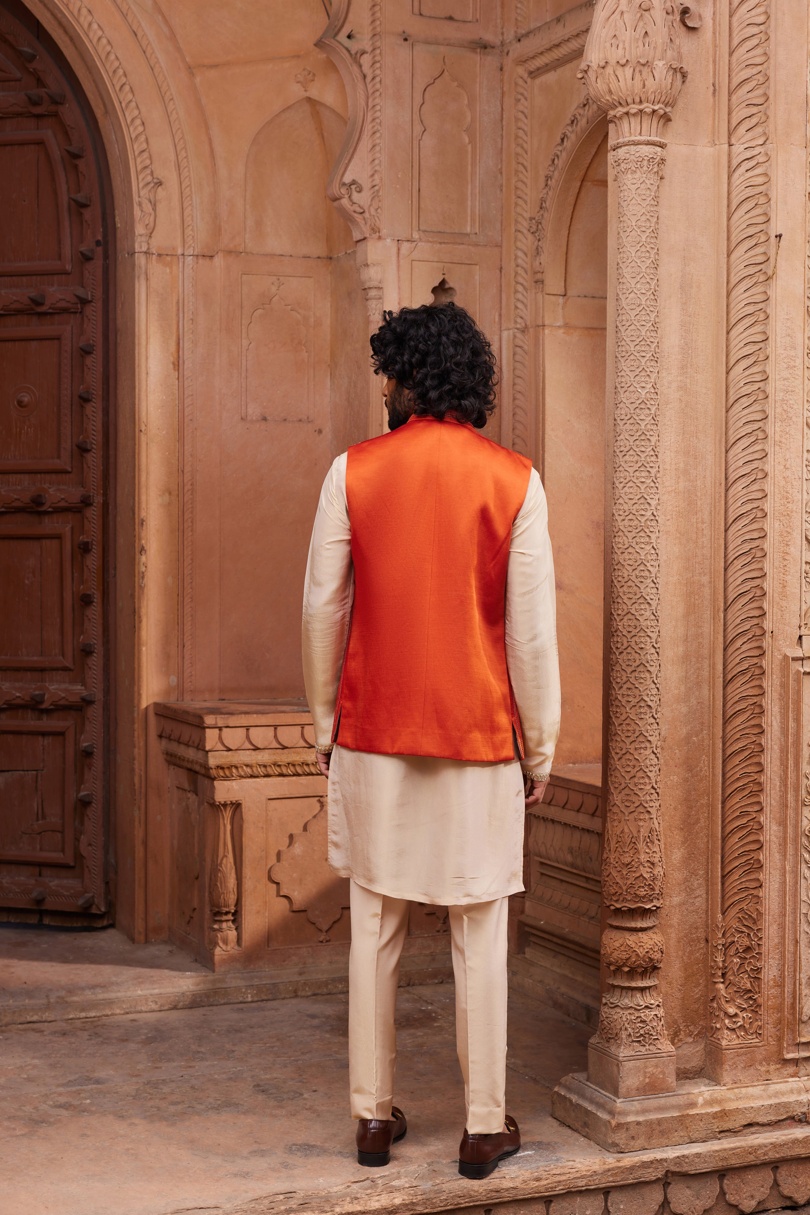 A stylish Rust Floral Nehru Jacket Set, highlighting a rust jacket with gold floral motifs and dori embroidery, paired with a beige detailed kurta at the hem and matching pants