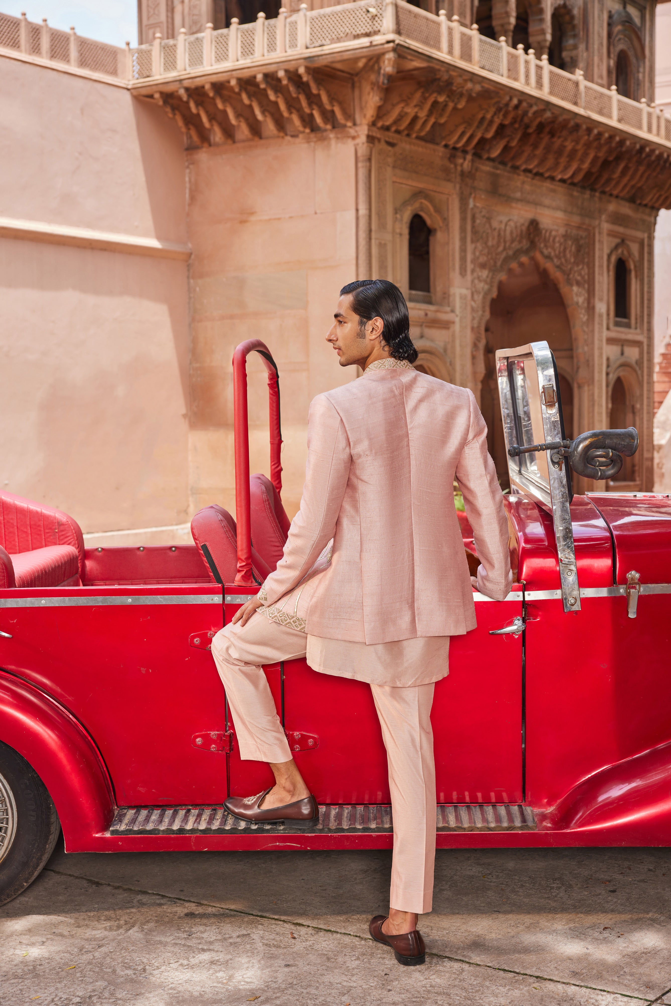 Full view of a jacket adorned with leather patchwork showcasing palm trees, floral motifs, and a geometric border, paired with a detailed kurta placket and pants for a bold and refined look.