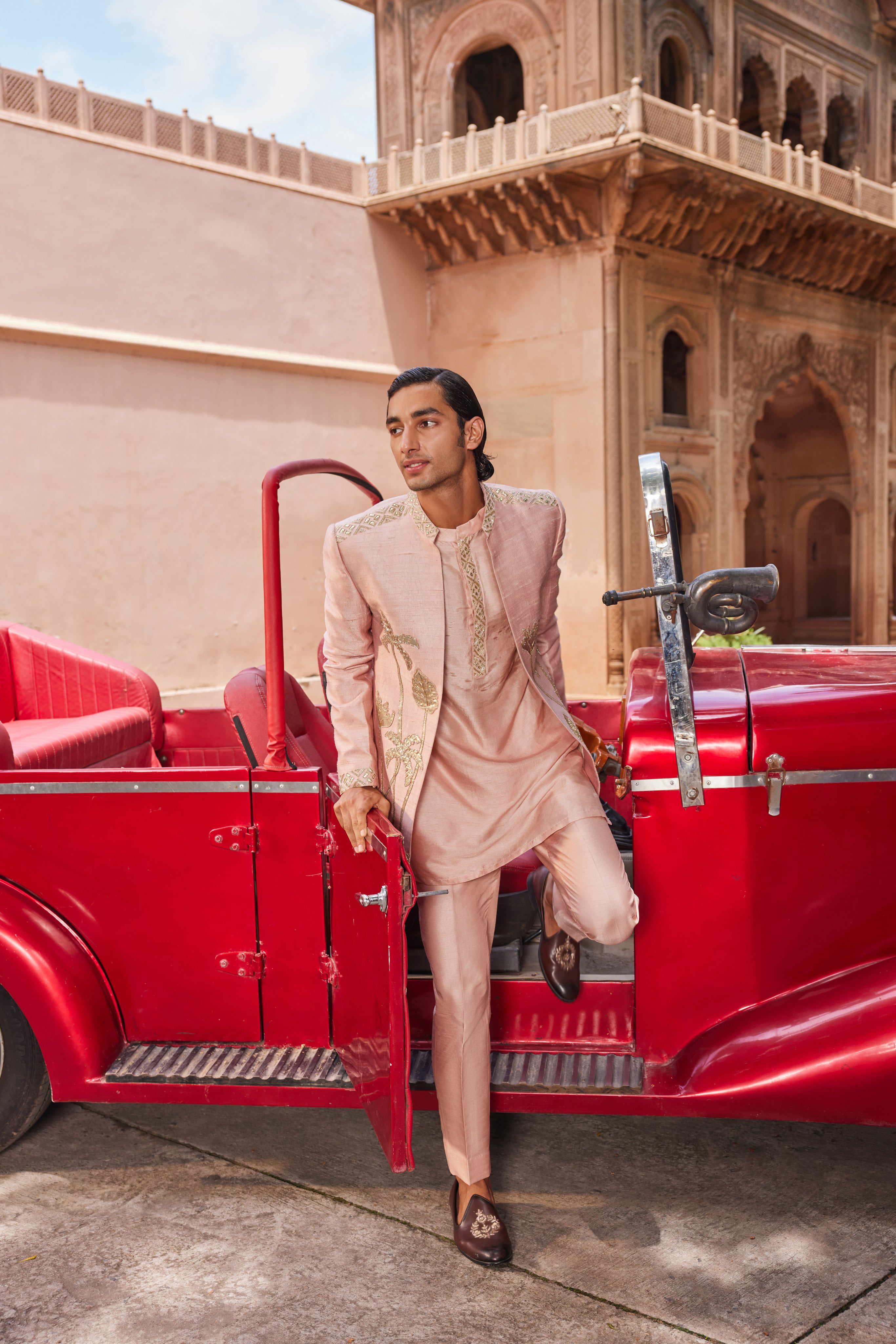 Full view of a jacket adorned with leather patchwork showcasing palm trees, floral motifs, and a geometric border, paired with a detailed kurta placket and pants for a bold and refined look.