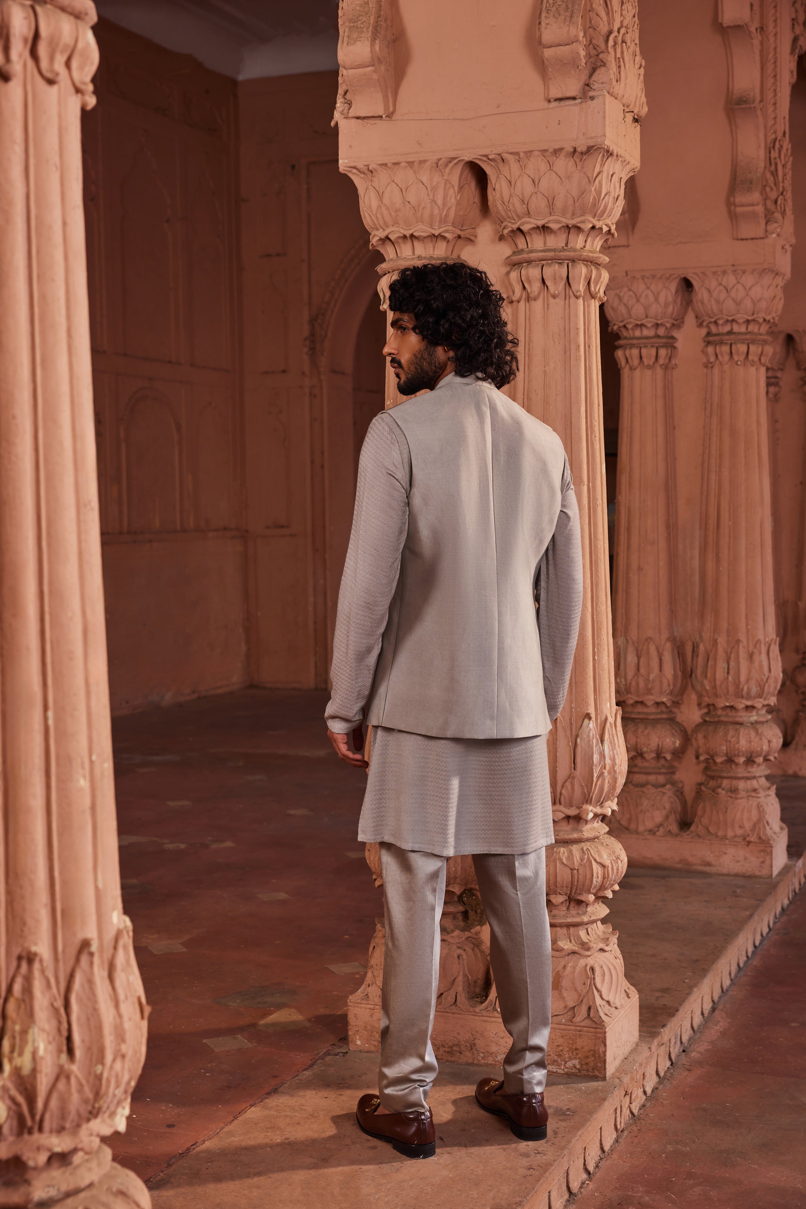 The Dusty Olive Handpaint Nehru Jacket Set includes a jacket with colorful floral motifs hand-painted and embellished with handwork, complemented by a simple monotone kurta and pants.