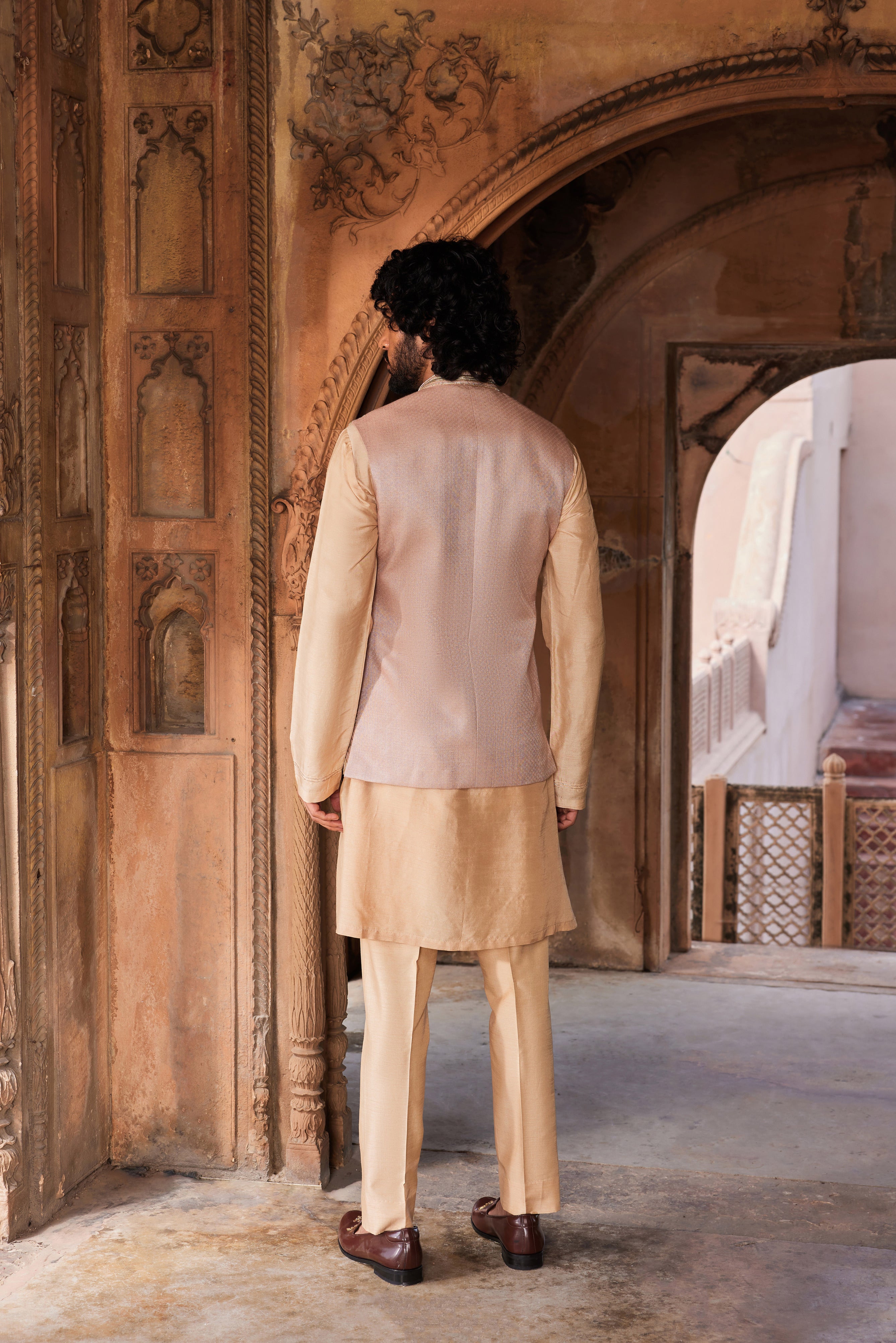 The Ibaadat Nehru Jacket Set includes a jacket with geometric patterns, enhanced by leather patch accents, kiran dori, and intricate resham and dabka embroidery. Paired with a detailed kurta and pants for a refined look.
