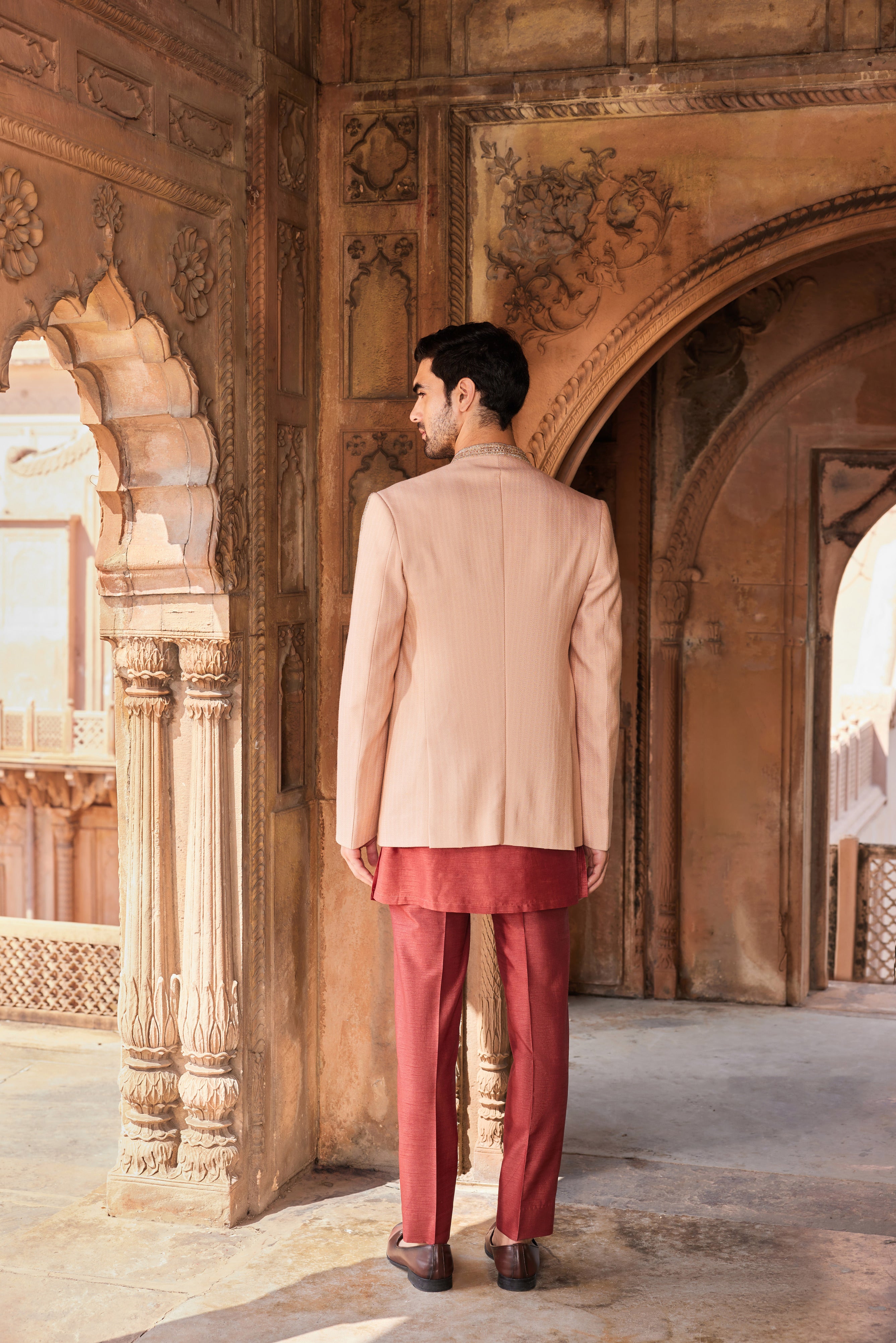 Close-up of a jacket showcasing finely detailed floral embroidery accented with cutdana, dabka, and zardozi, complemented by a contrasting kurta and pants.