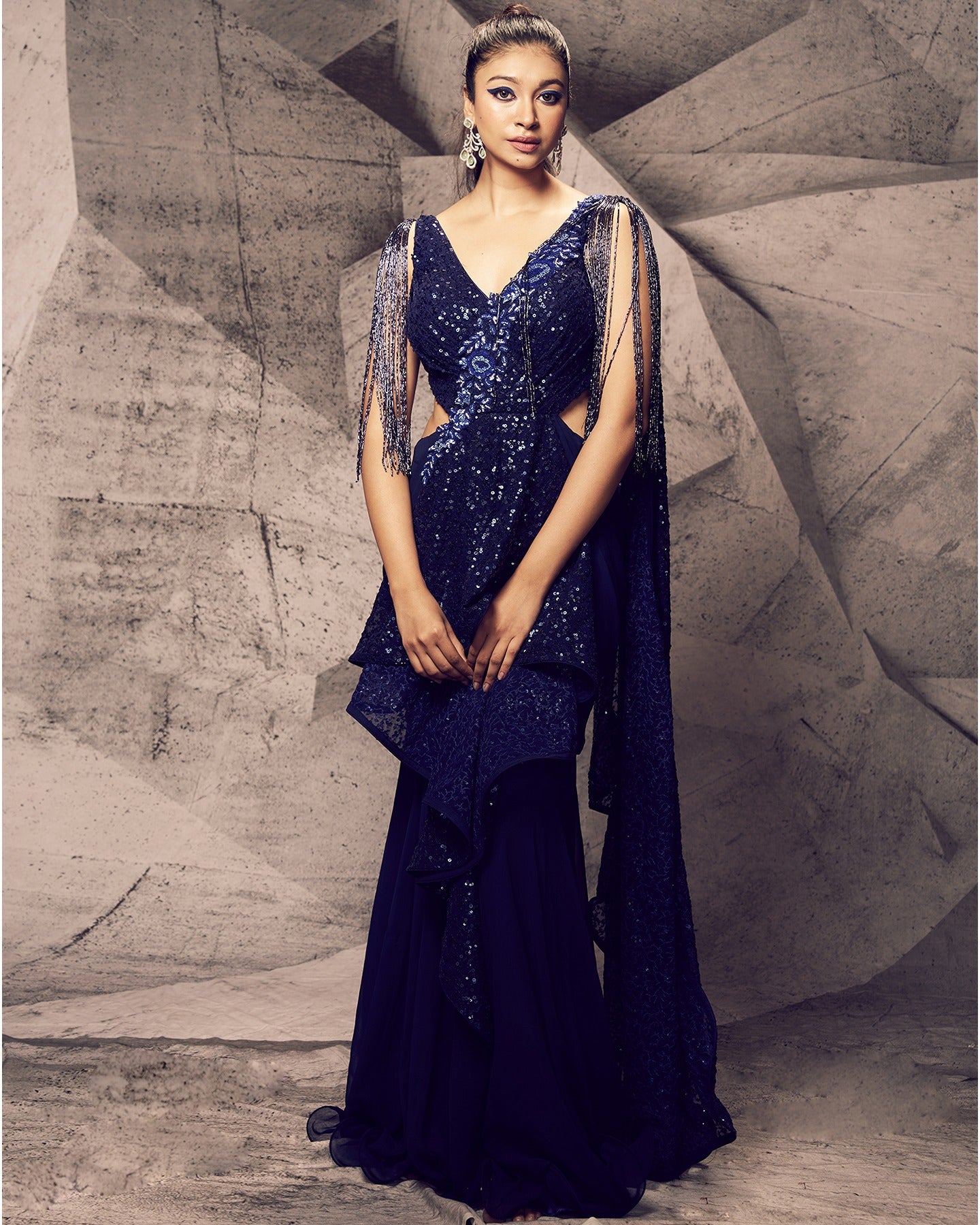 Draped in the captivating hues of blue, this gown saree is a canvas of elegance and opulence, adorned with floral embroidery, stones, sequins, and kardana beads for a touch of glamorous allure. 