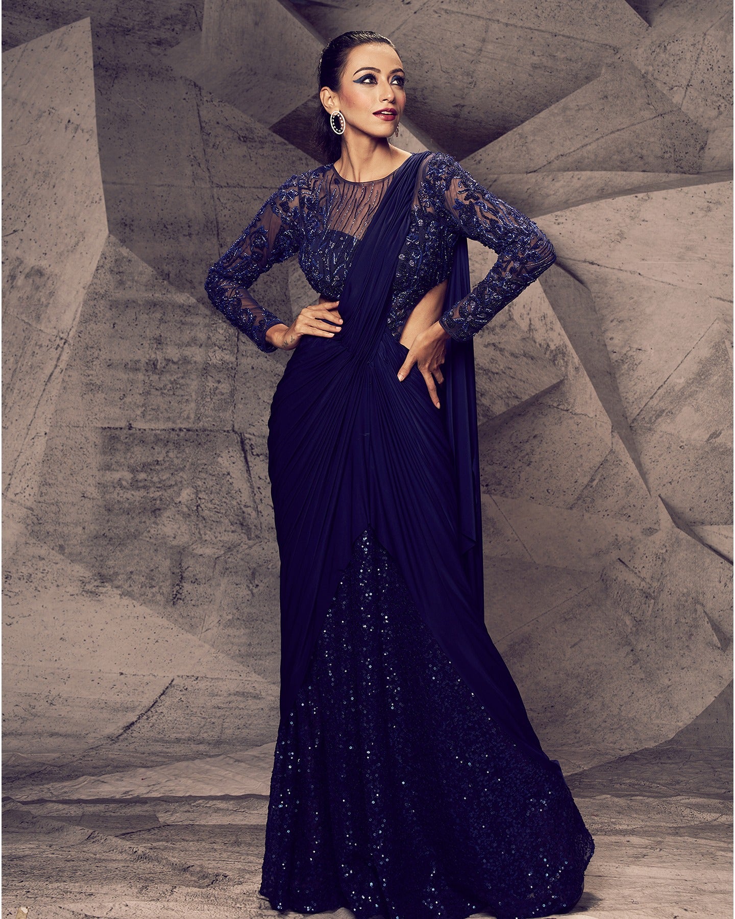 Draped in the enchanting hues of blue, this saree with a flowing lycra drape and sequin-embroidered pleats is a symphony of grace and sophistication, ready to make a statement.