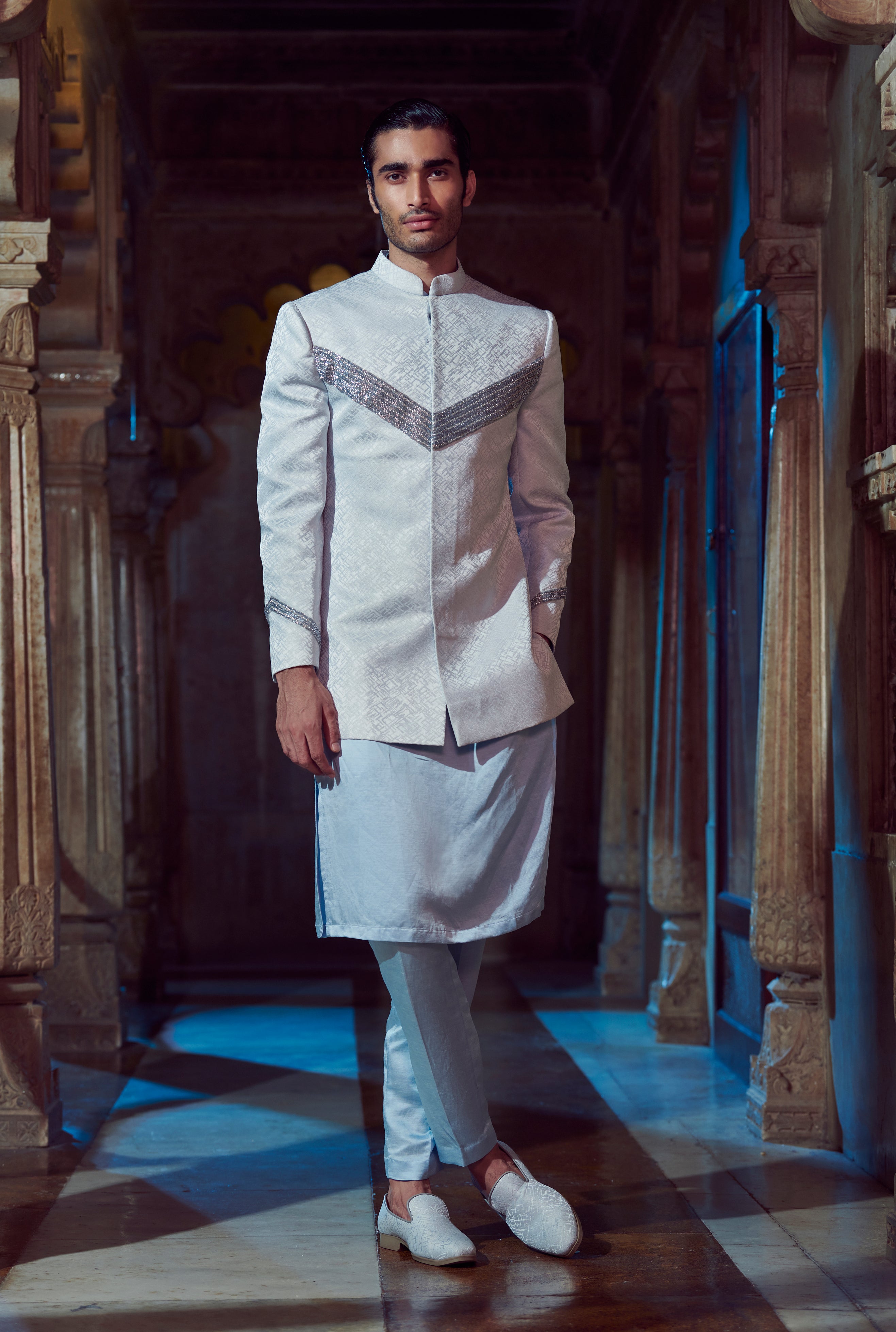 Embrace bespoke elegance with our customizable ensemble featuring a textured fabric jacket adorned with V-shaped embroidery. Paired flawlessly with Linen Satin Kurta and Pants in serene pale blue.