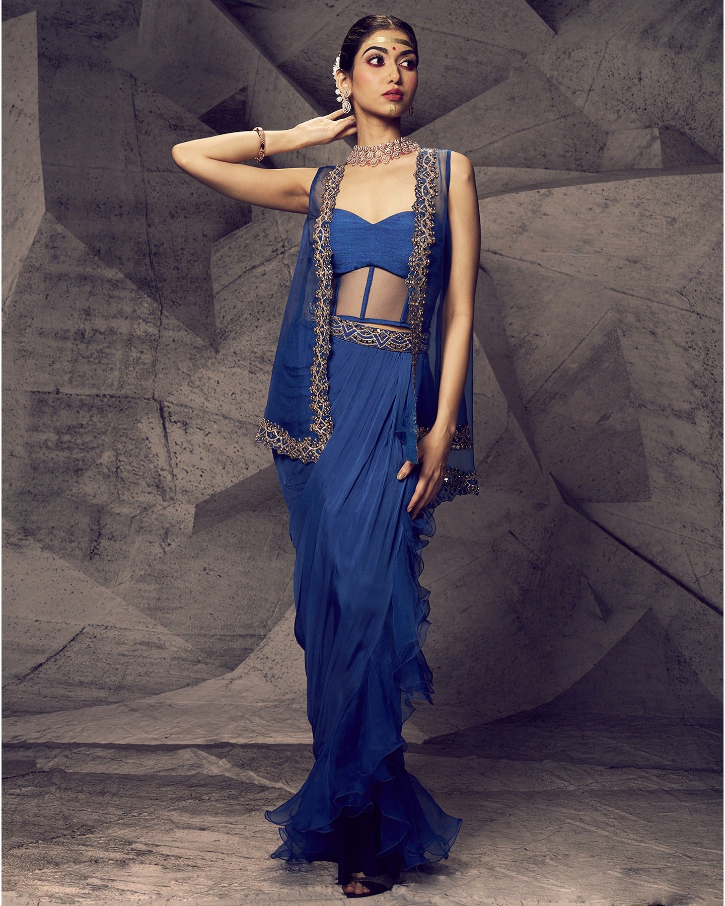 Drenched in bold blue hues and adorned with shimmering mirror work, this dhoti skirt and jacket ensemble is a modern symphony of elegance.