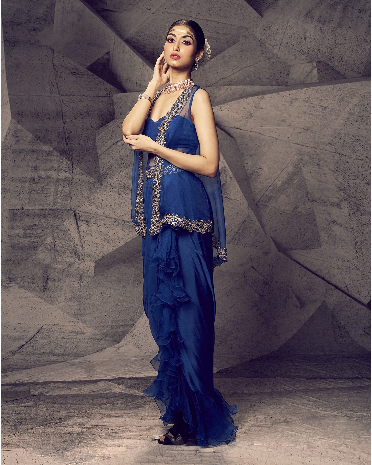 Drenched in bold blue hues and adorned with shimmering mirror work, this dhoti skirt and jacket ensemble is a modern symphony of elegance.