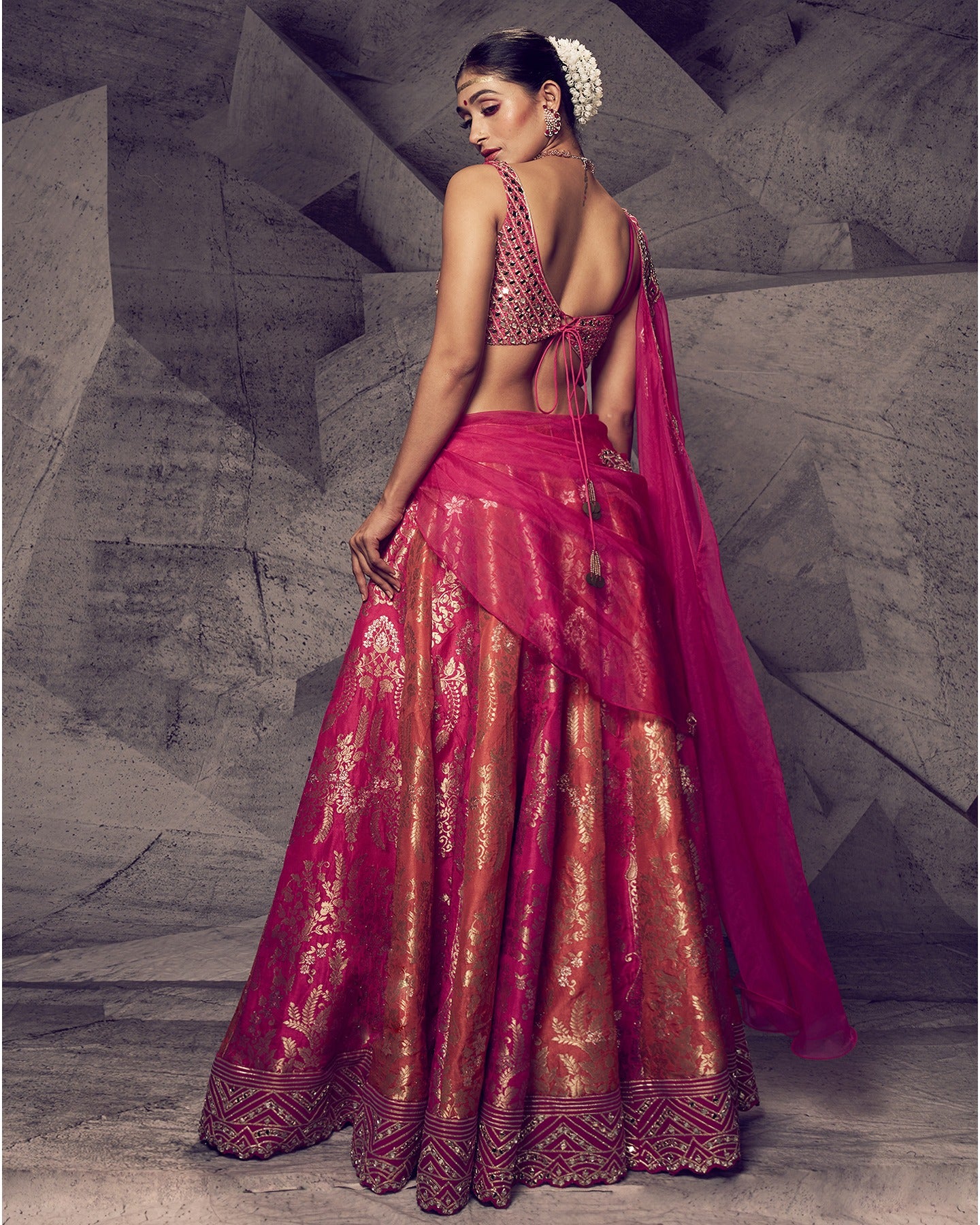 Drenched in the royal hues of rani pink, this lehenga is a symphony of opulent details. 