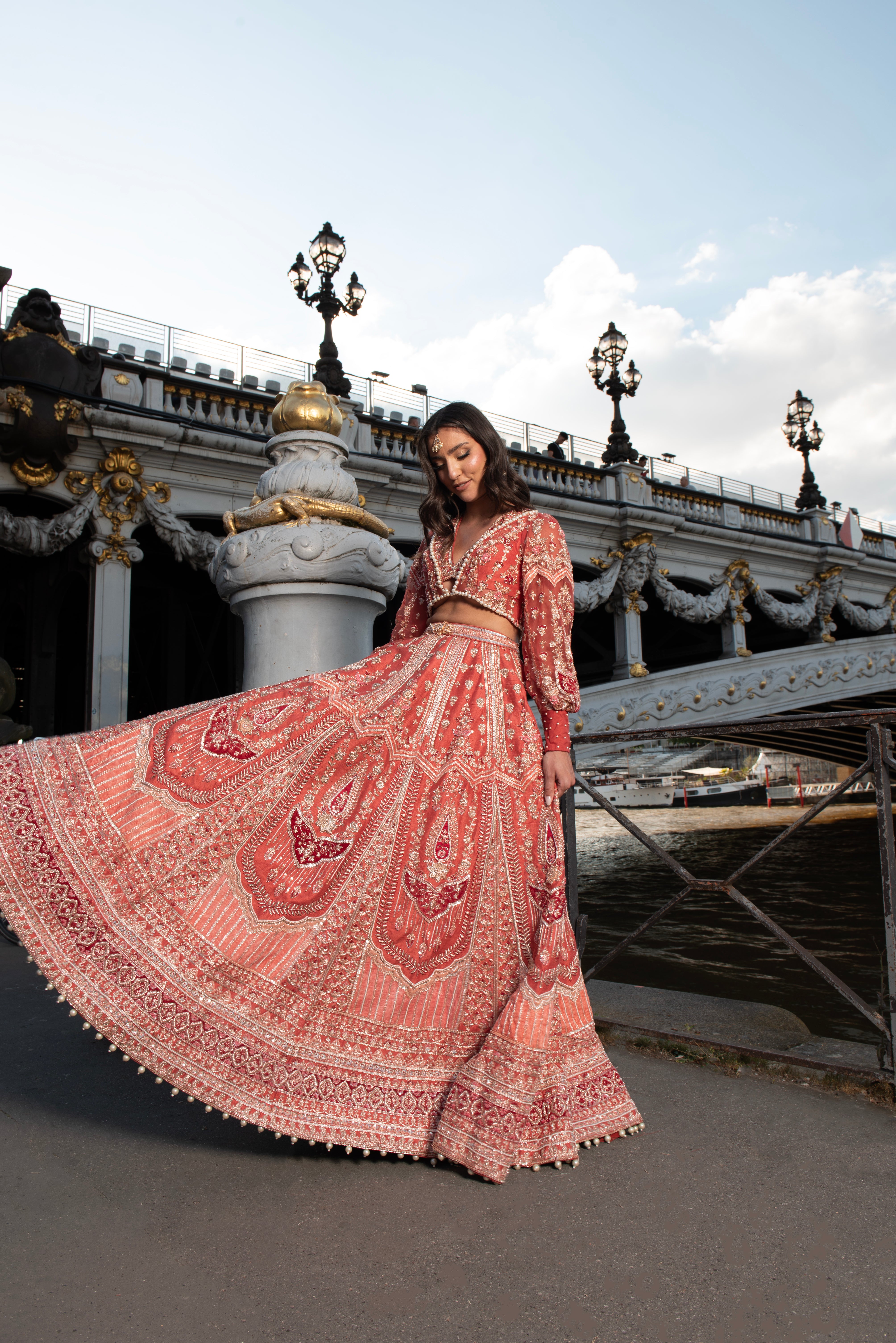 Red modern lehenga set with detailed embroidery on raw silk and velvet. The ensemble includes a net blouse with a 'Koti' style and puff sleeves, blending Indian tradition with European flair