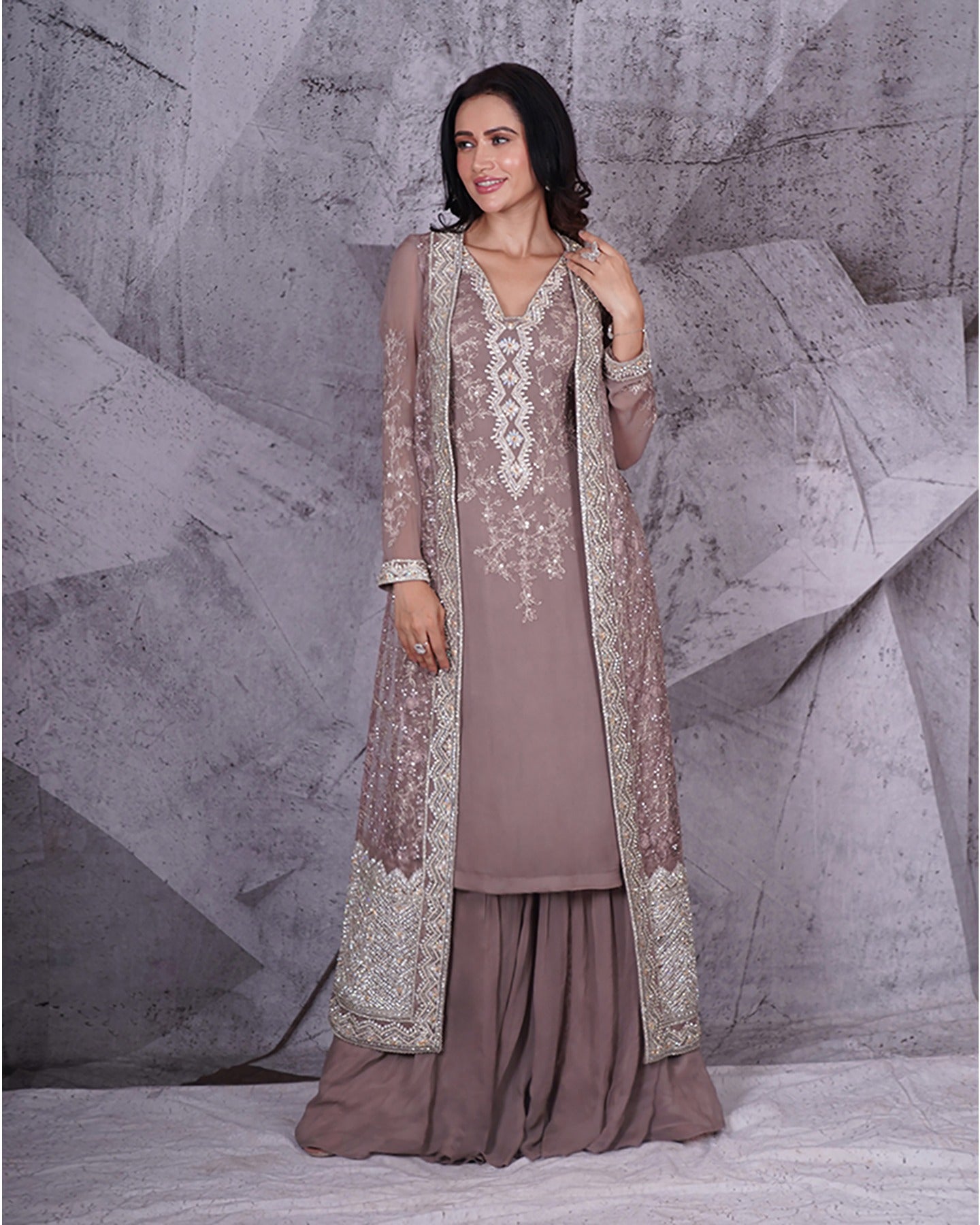 Draped in the sophistication of grey, this jacket sharara set blooms with shimmering floral silver embroidery.