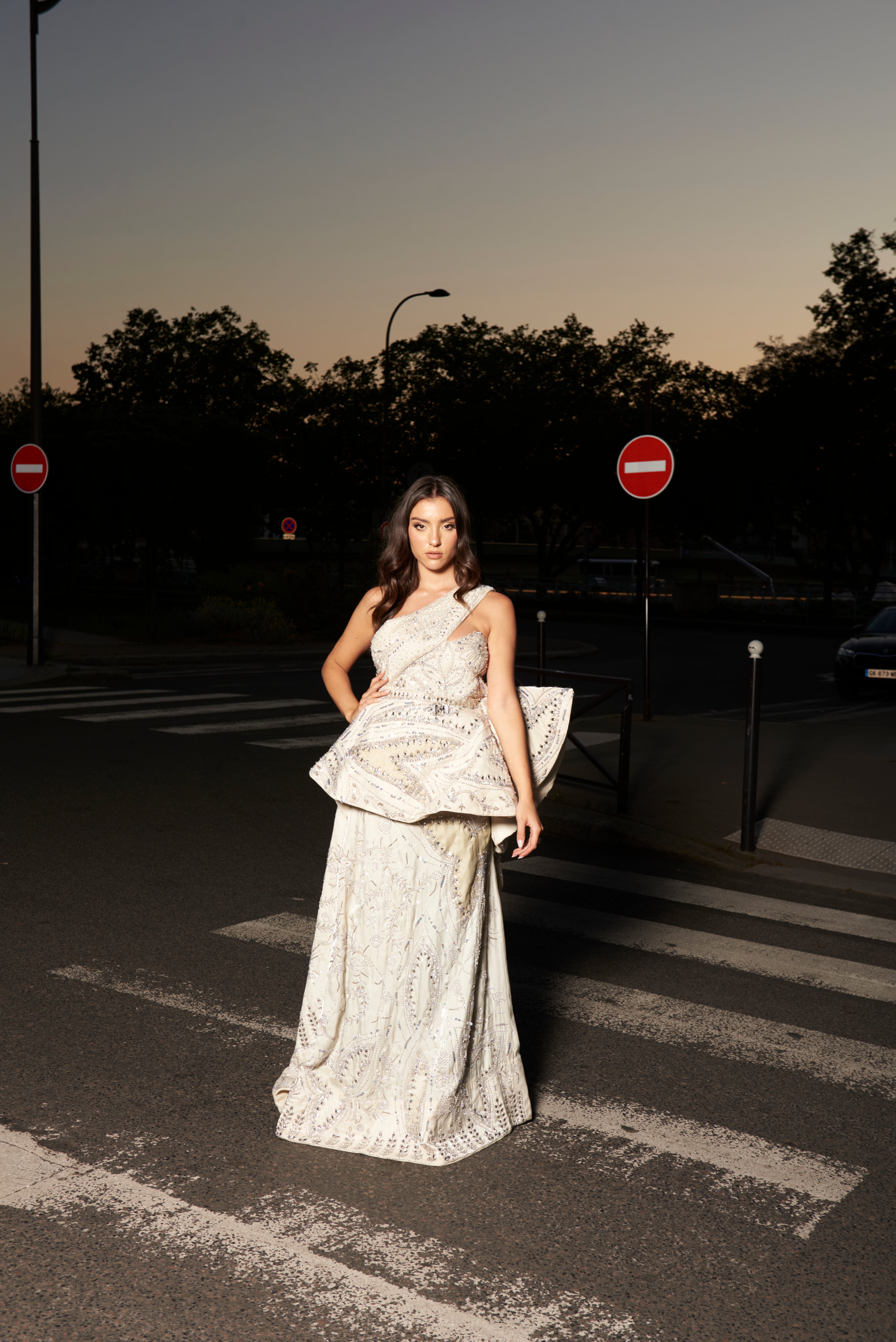 Ivory one-shoulder gown crafted from glass organza, featuring exquisite handcrafted embroidery. The gown’s stunning silhouette elegantly accentuates the figure