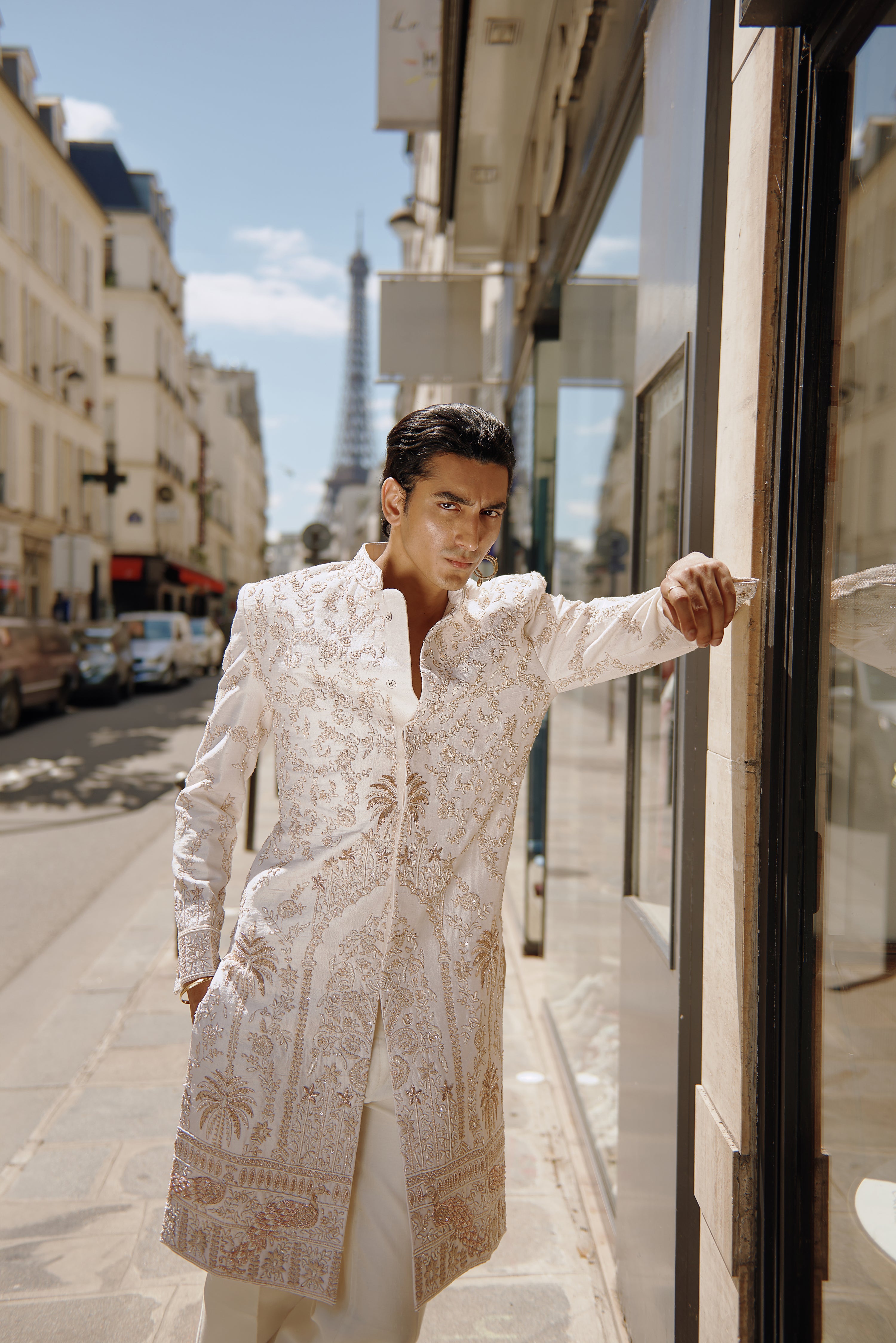 White sherwani set with intricate handwork and gold embroidered motifs, crafted from raw silk. Paired with a Chanderi silk kurta, pant, and a linen satin dupatta, this ensemble radiates elegance