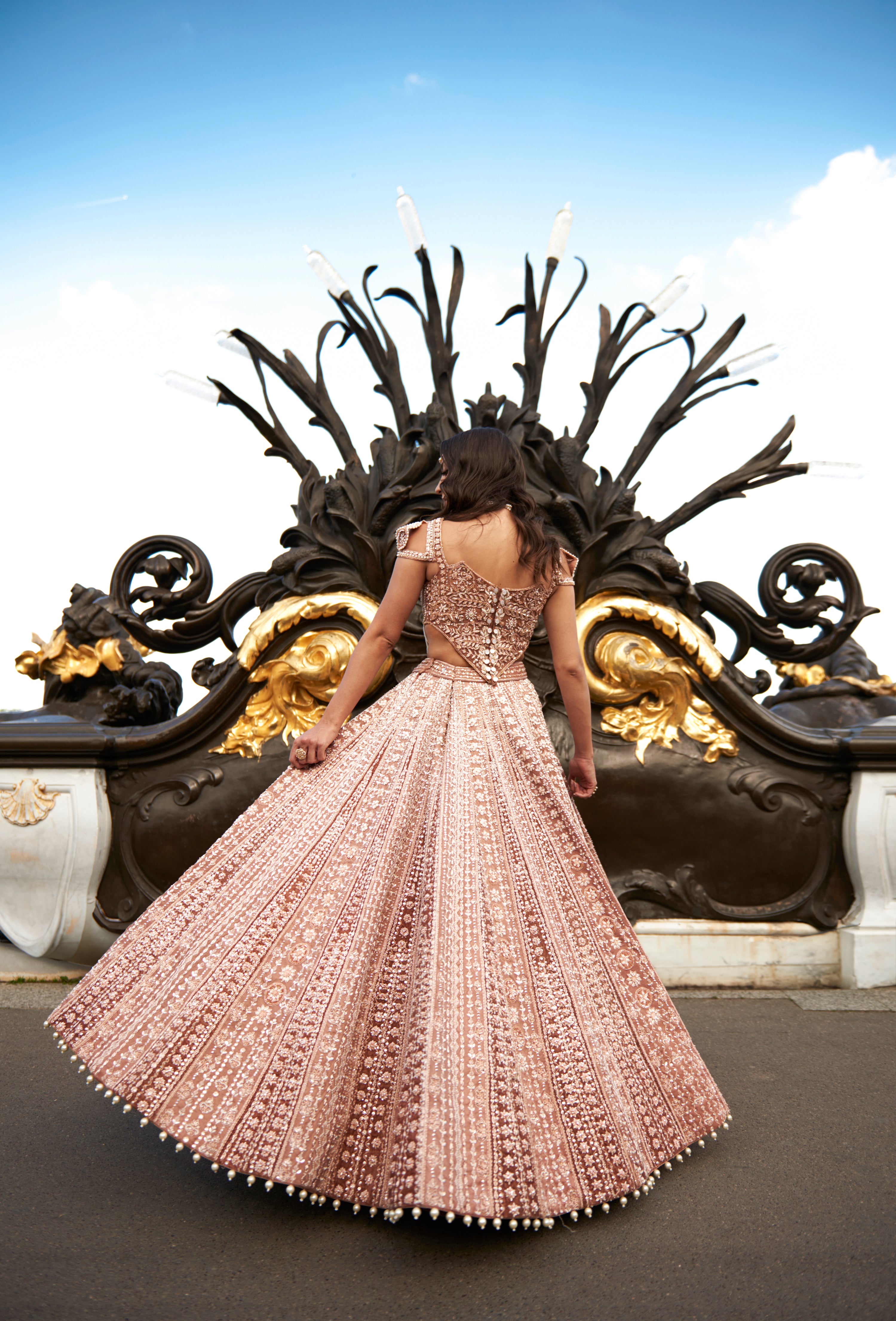 Brown lehenga set in caramel shade, featuring hand embroidery, pearl accents, and pearl danglers. The linen silk lehenga and sea shell silhouette blouse, paired with a net dupatta, offer a timeless and ethereal look.