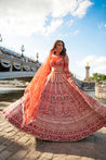 Elegant full-sleeve red lehenga set in carnelian red, showcasing meticulous hand embroidery and pearl details on raw silk and velvet, completed with a net blouse and dupatta for added sophistication