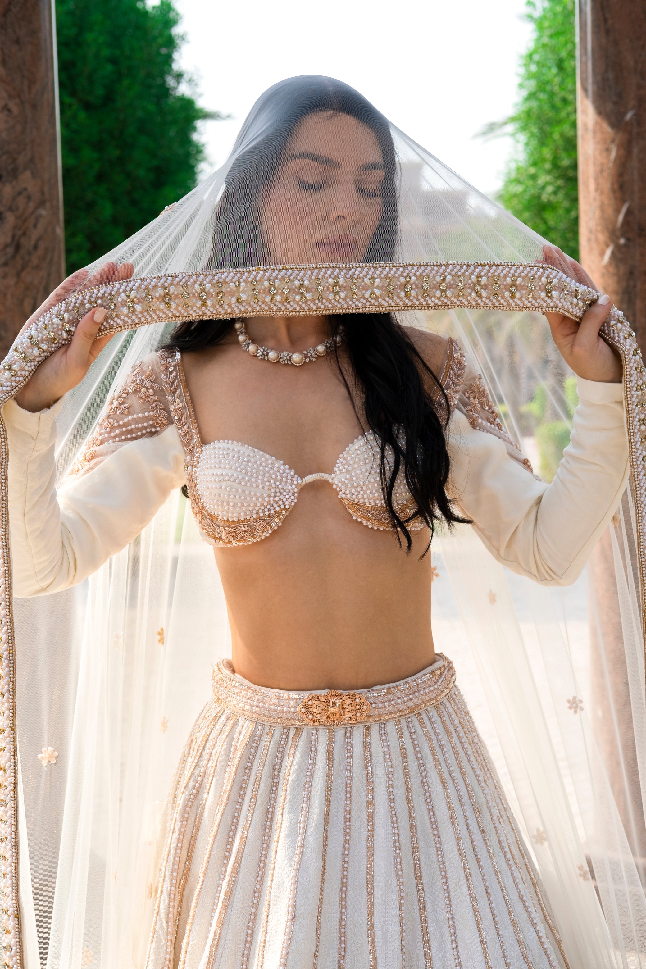 Pearl white linen satin lehenga with intricate Chikankari work, full-sleeved blouse adorned with pearls, and a light net dupatta