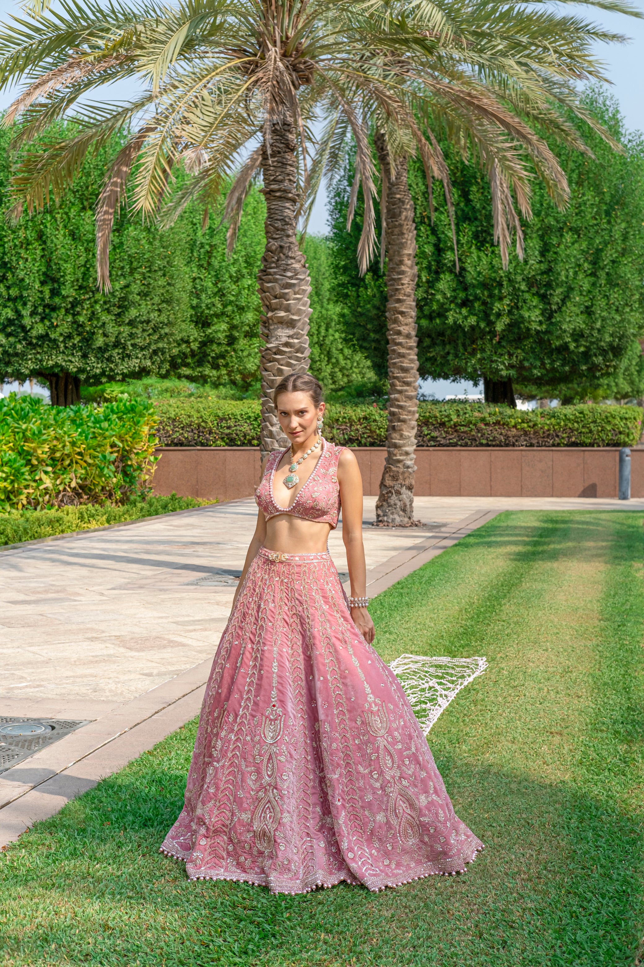 Salmon pink velvet lehenga with a sleek sleeveless blouse and a delicate net dupatta for an elegant contrast