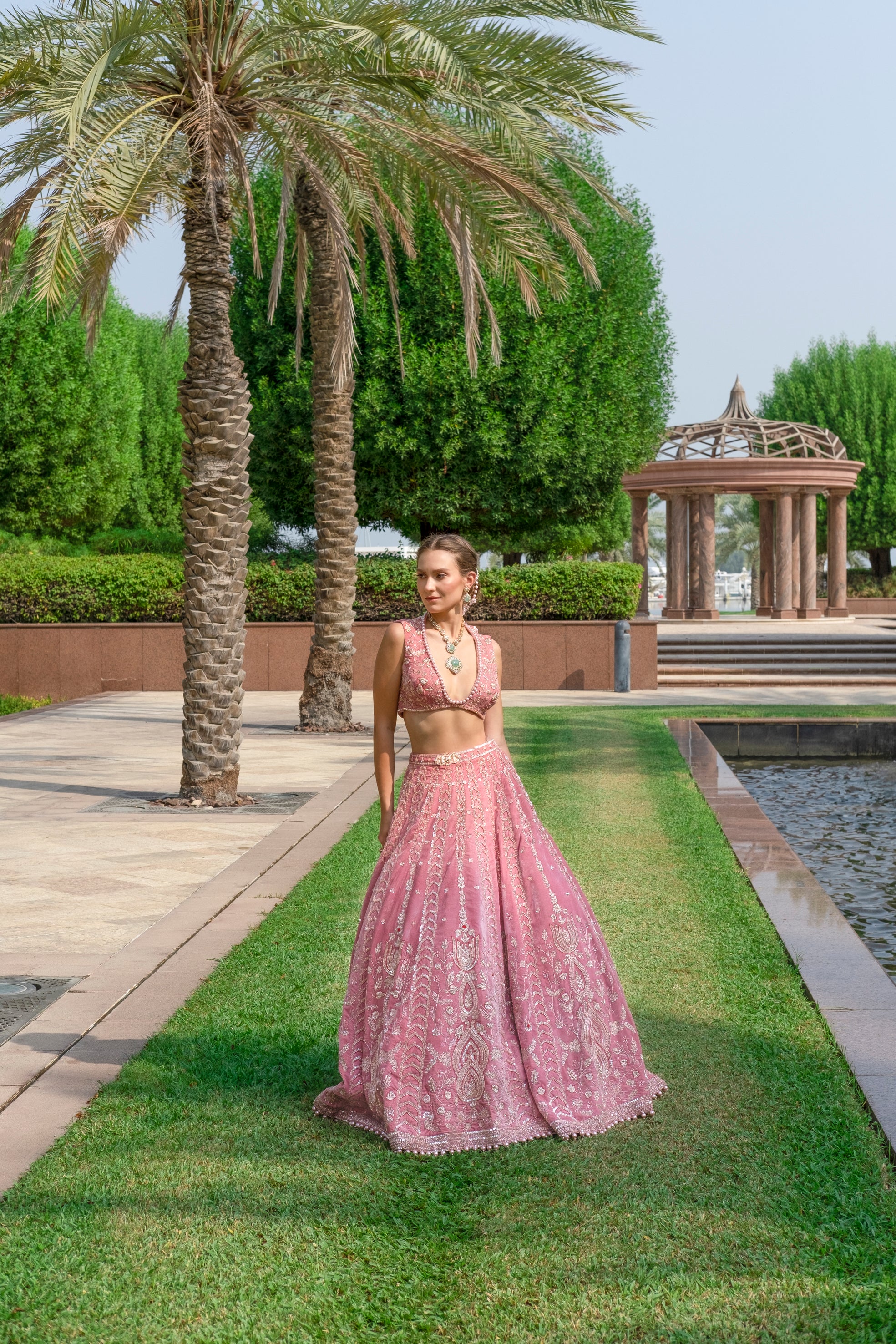 Velvet lehenga in salmon pink with a chic V-neck sleeveless blouse, paired with a light, airy net dupatta.