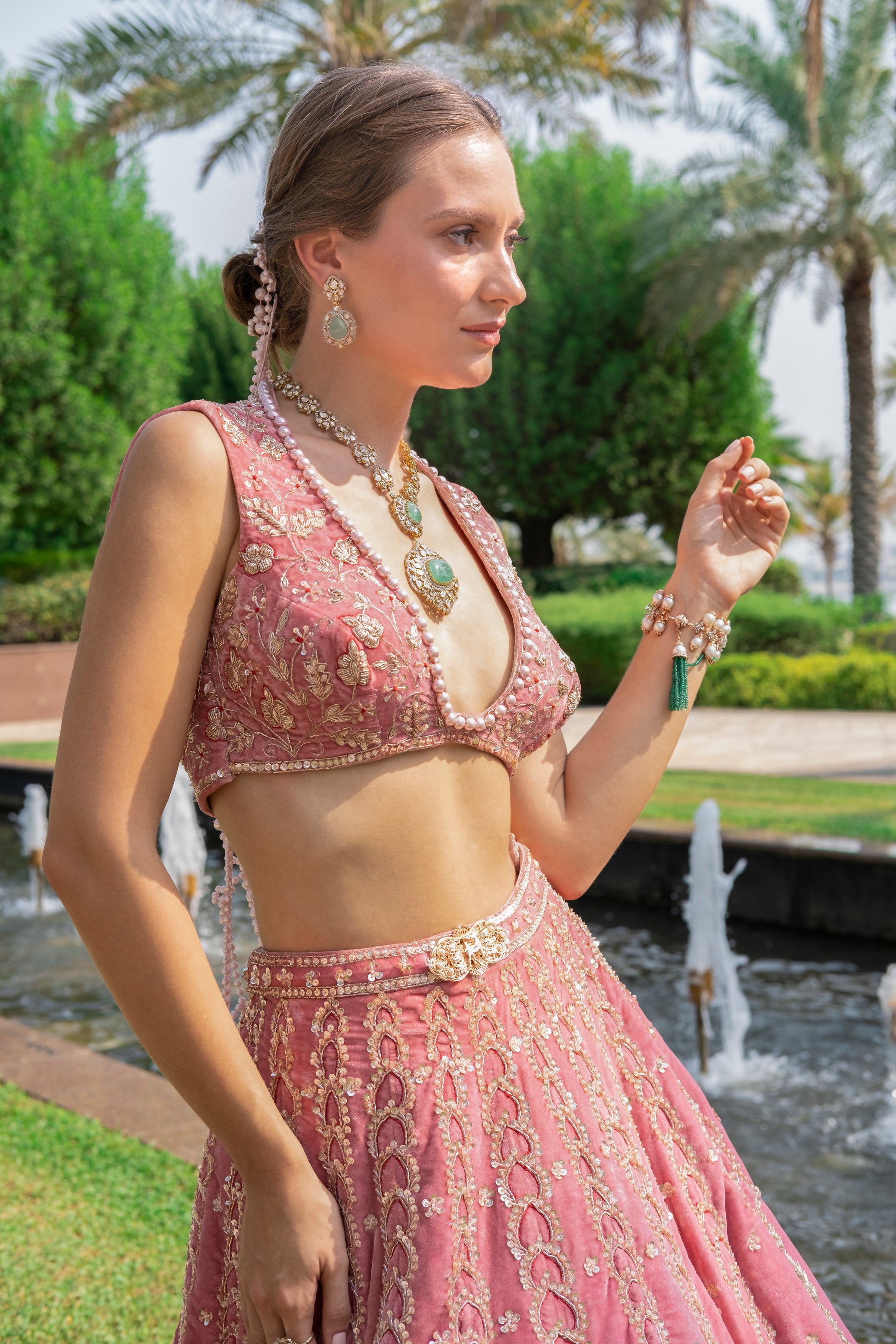 Luxurious salmon pink velvet lehenga set featuring a V-neck sleeveless blouse and a graceful net dupatta