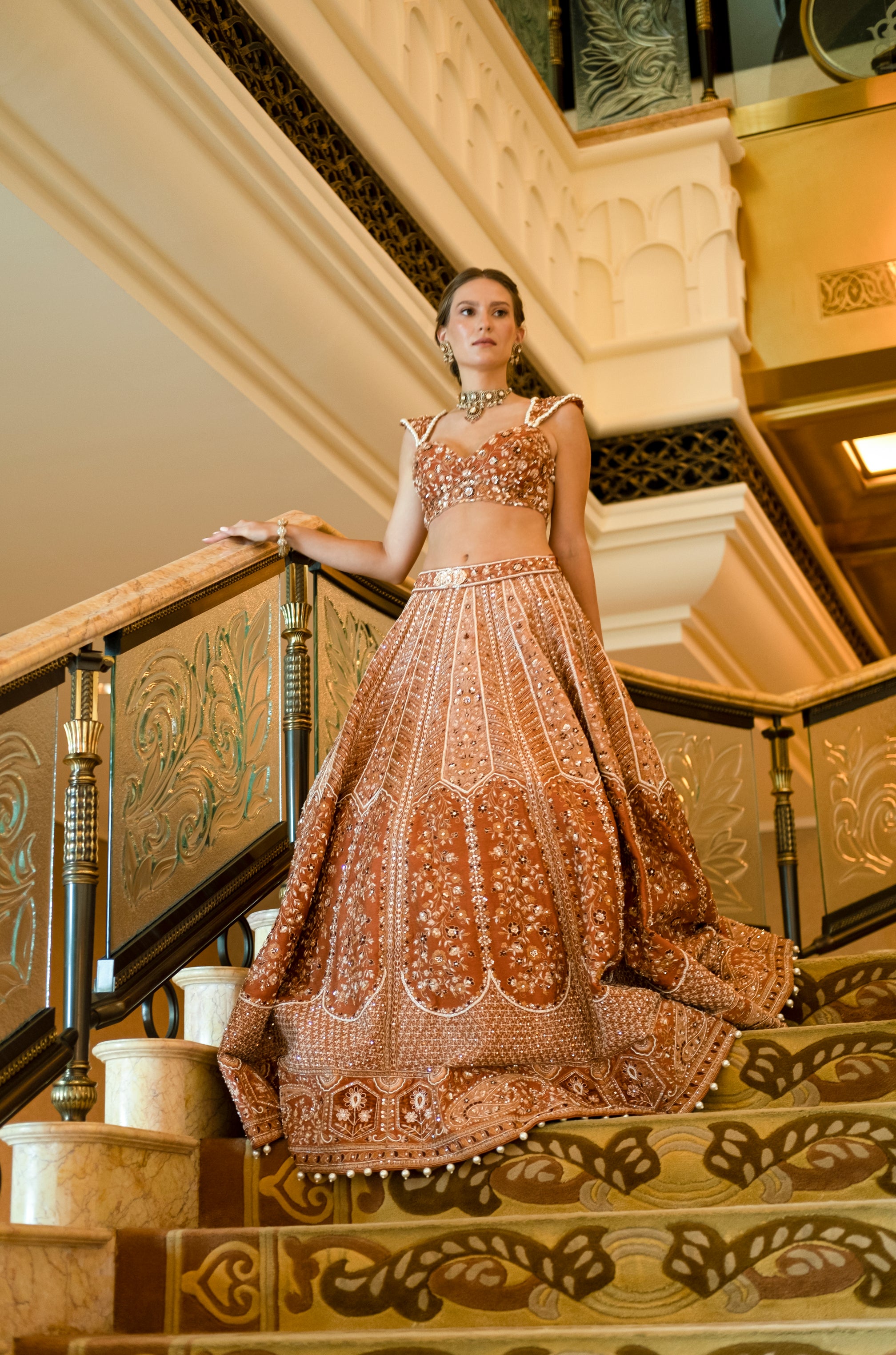 Rich ochre rust lehenga set with a silk-net blouse and a net dupatta adorned with exquisite velvet applique and traditional handwork.