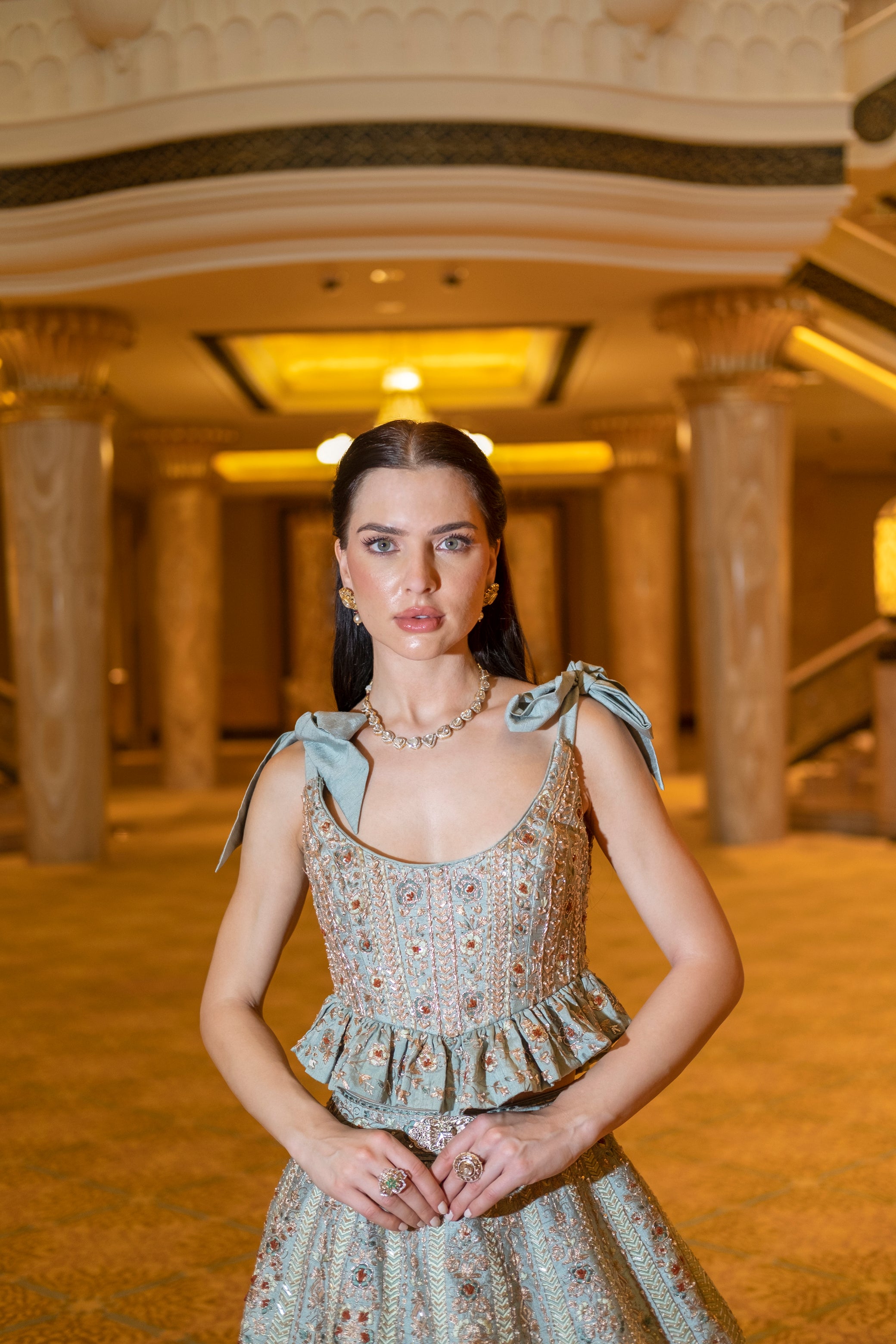 Serene green lehenga set in raw silk and velvet, adorned with teal velvet appliqué, paired with a short peplum blouse and airy net dupatta.