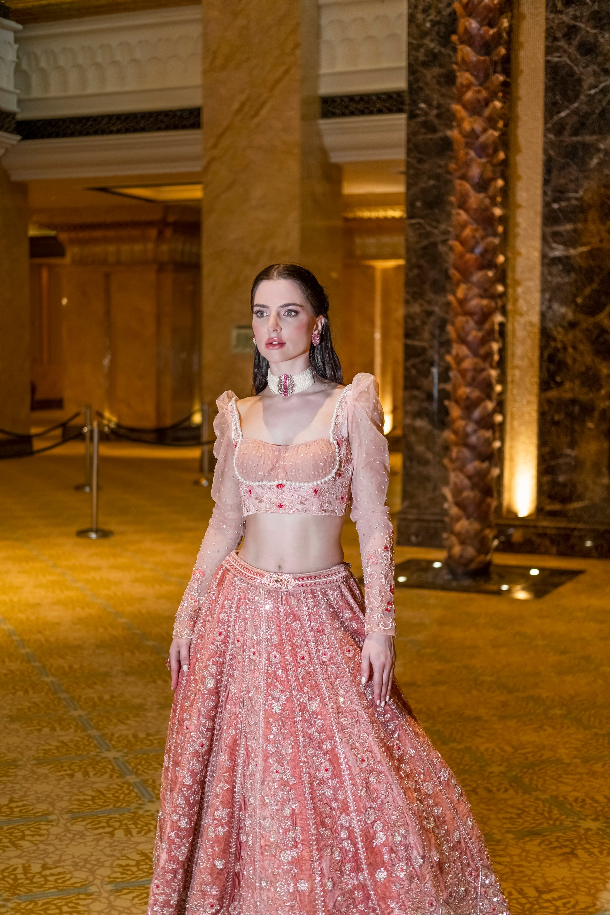 Luxurious peach velvet lehenga with vertical panel embroidery, paired with a matching blouse and net dupatta featuring delicate cutwork