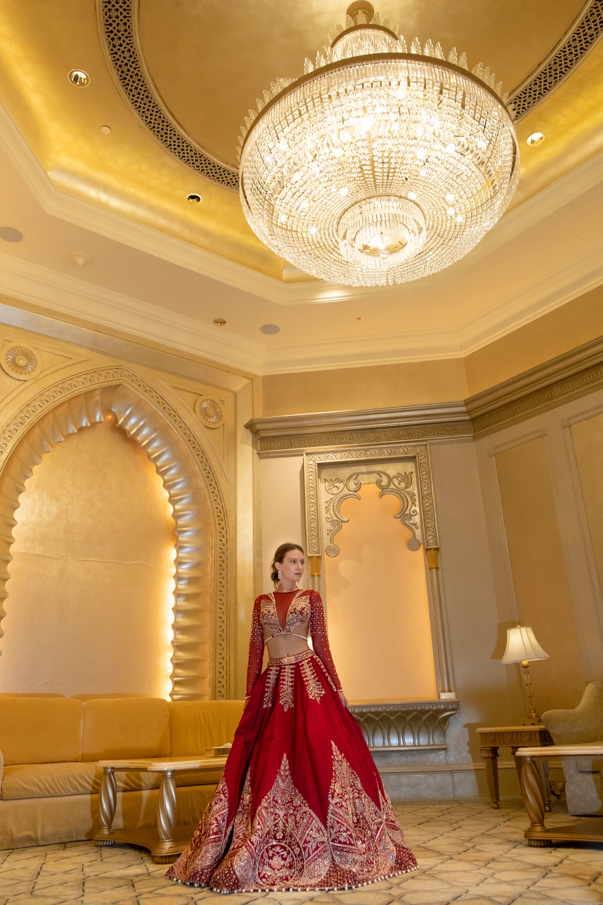 Luxurious ruby red linen satin lehenga with intricate gold zardoshi embroidery, paired with a high-neck net blouse and sheer full sleeves.