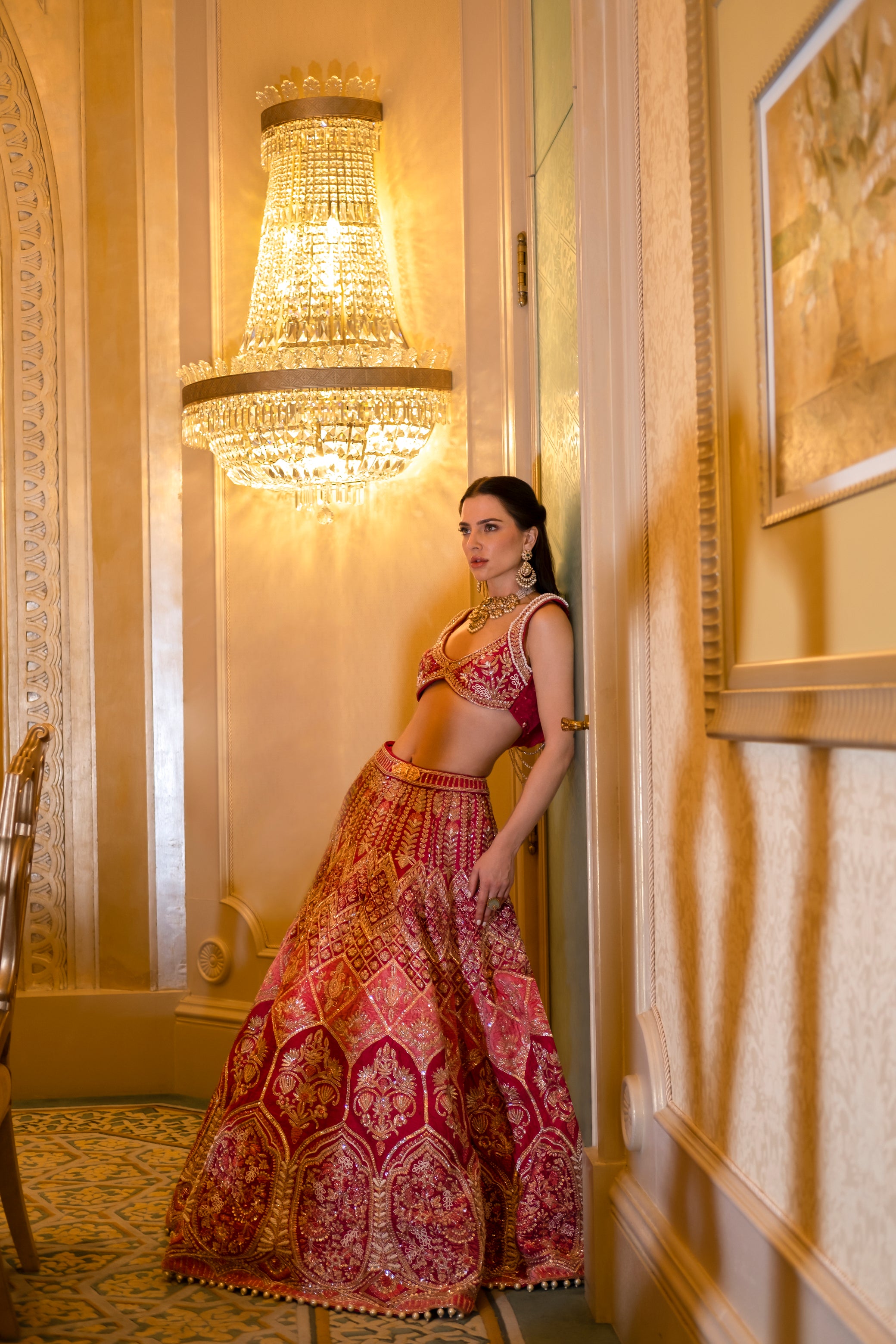 Vibrant cerise pink lehenga with detailed mukaish, pearl, and zardoshi work, paired with a cowl-neck blouse and sheer net dupatta.