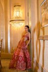 Vibrant cerise pink lehenga with detailed mukaish, pearl, and zardoshi work, paired with a cowl-neck blouse and sheer net dupatta.