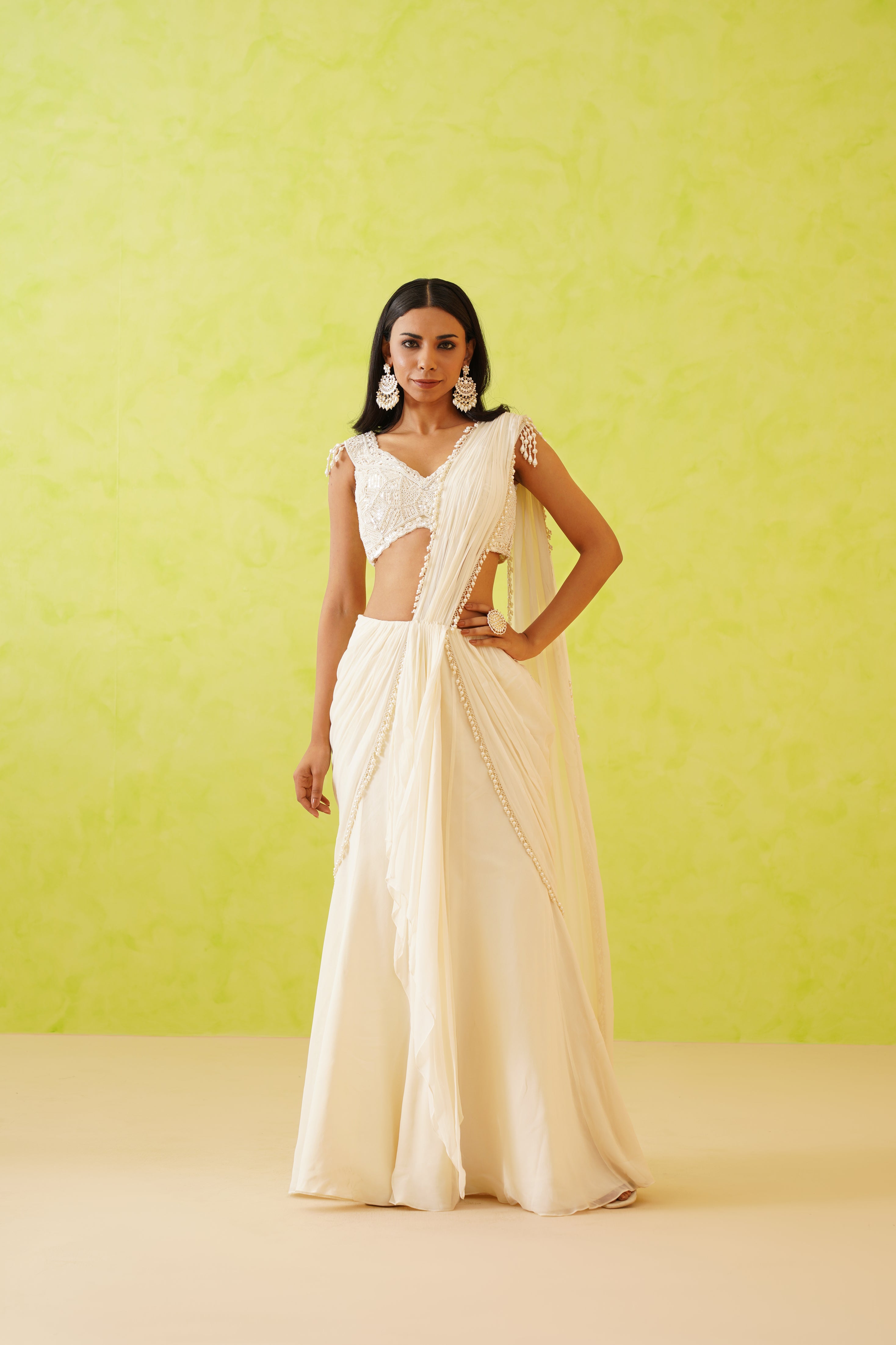 Chic white saree with a modern flowy drape, styled with a blouse embellished with floral patterns made from sequins, stones, crystals, and pearls.