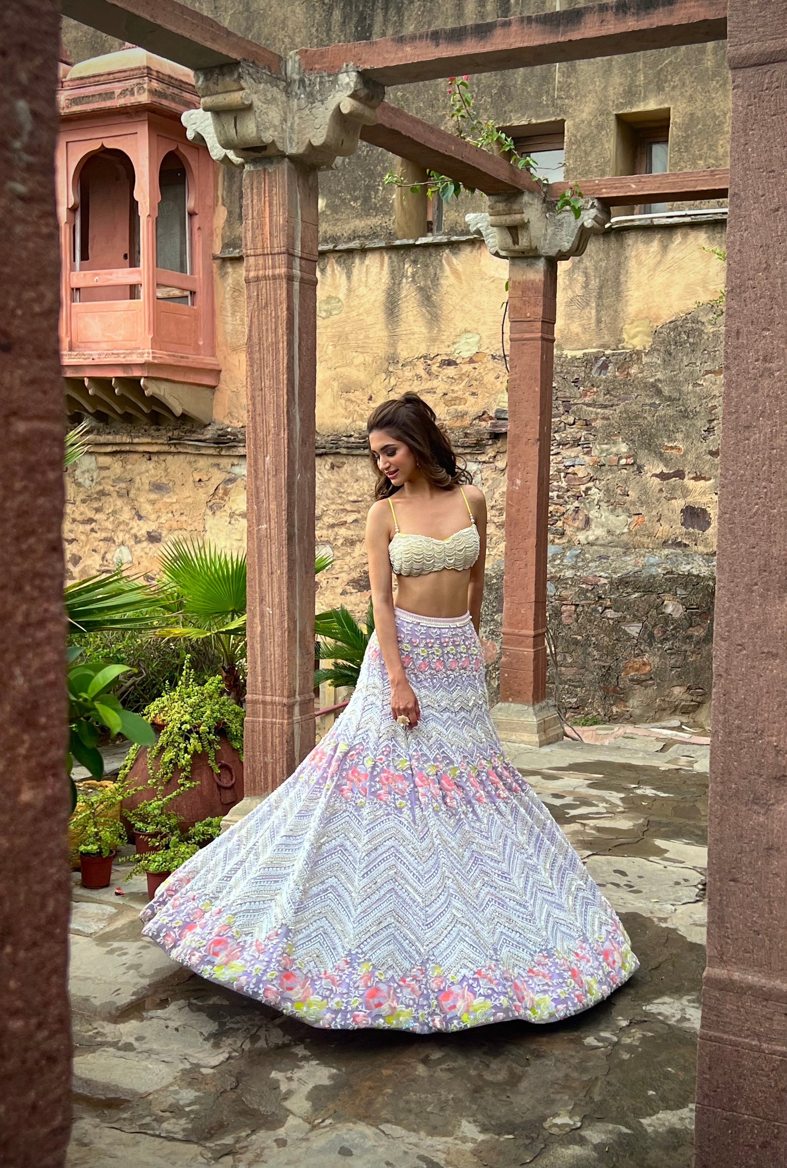 The Alara Mermaid Lehenga, designed for the modern Cinderella bride, includes a crystal tassel choli and a metallic georgette lehenga with exquisite chevron and floral patterns