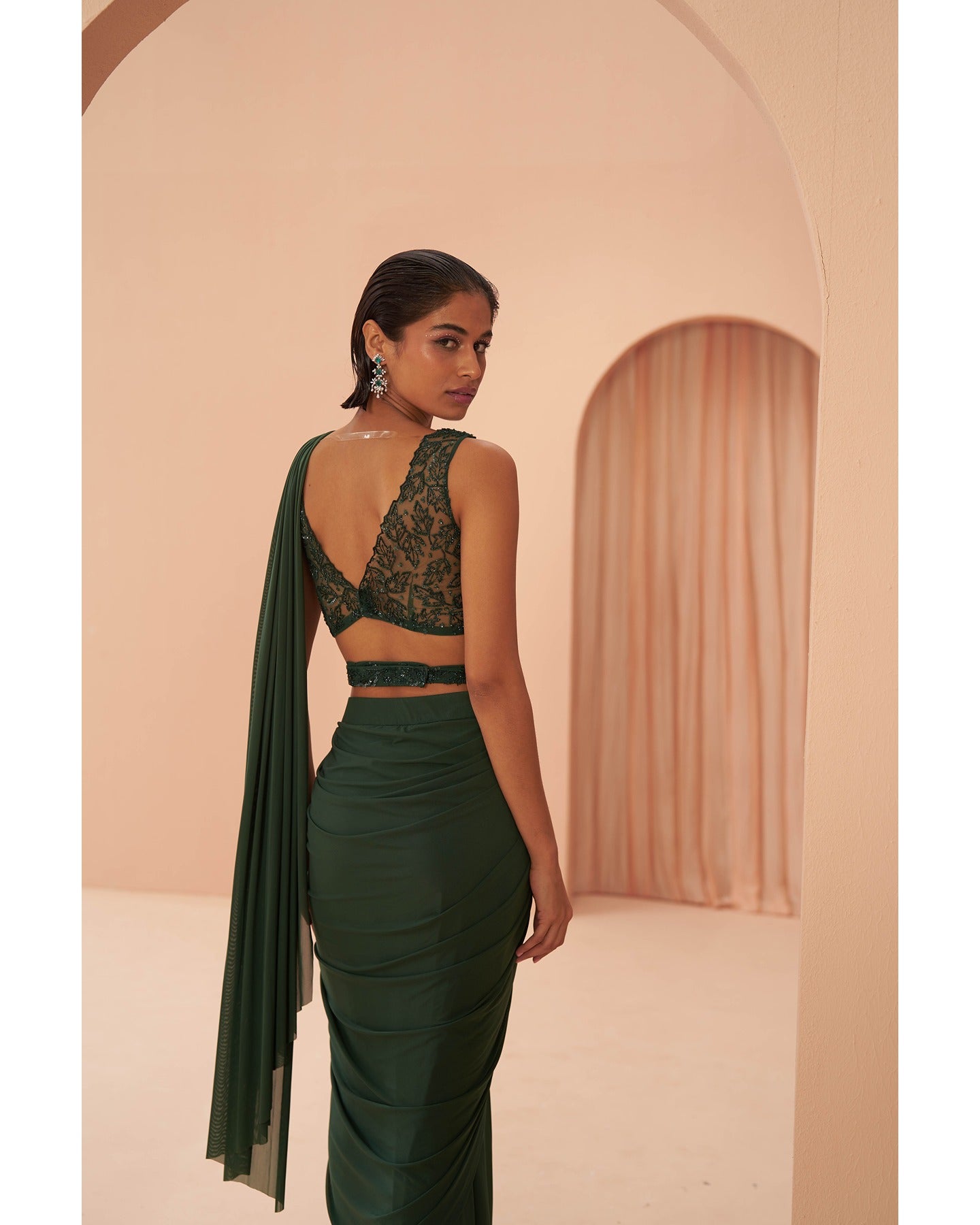 Bottled Beauty: Hand-embroidered elegance adorns this bottle green drape saree, a captivating symphony of sophistication.