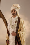 stunning white Jamawar sherwani, adorned with intricate dual-color flower details and highlighted with dabka embroidery for added elegance
